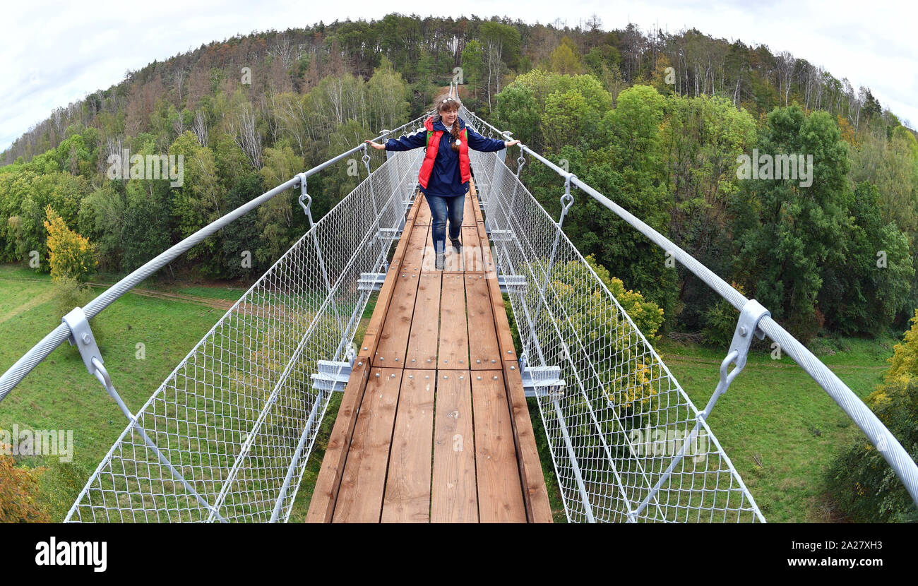 Erfurt, Germany. 01st Oct, 2019. Karin Jordanland from the association 'Hohe Schrecke - Alter Wald mit Zukunft e.V' crosses the first suspension bridge in Thuringia. The 176 meter long bridge in the north of the Hohe Schrecke mountain range (Kyffhäuserkreis) is stretched about 25 meters above the abyss of the Bärental. It is to be part of a three-kilometer circular hiking trail in the future. Credit: Martin Schutt/dpa-Zentralbild/dpa/Alamy Live News Stock Photo