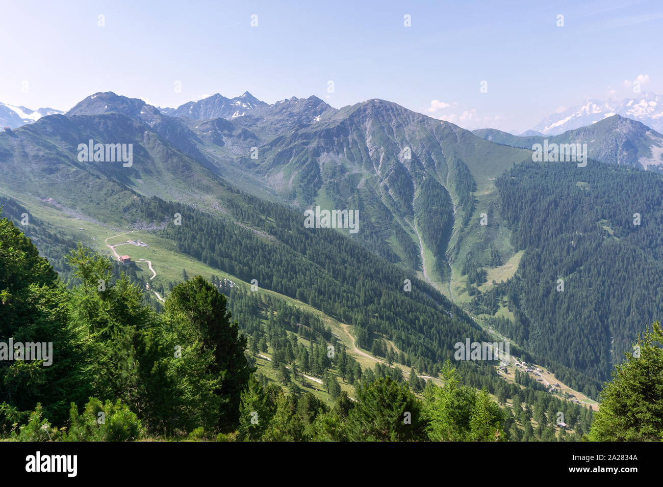 Mountains in the Swiss Alps, with wooded slopes and a mountain road. Stock Photo