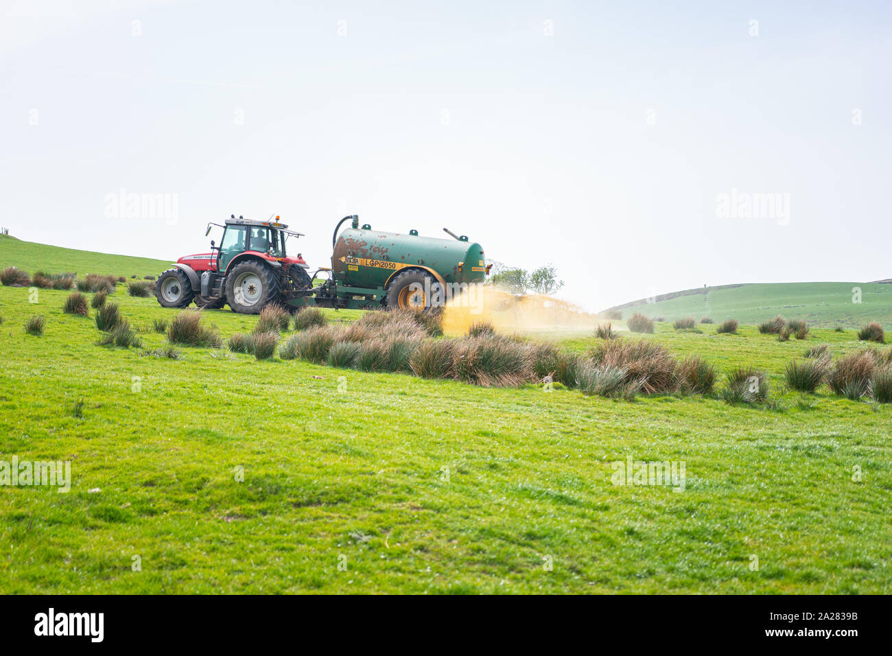 Tractor and farmer muck spreading in field Stock Photo Alamy