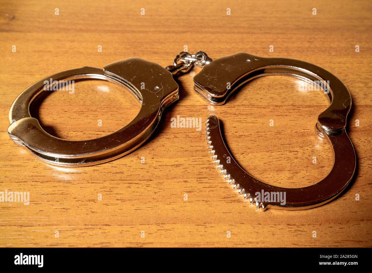 Open handcuffs on a wooden table closeup Stock Photo Alamy