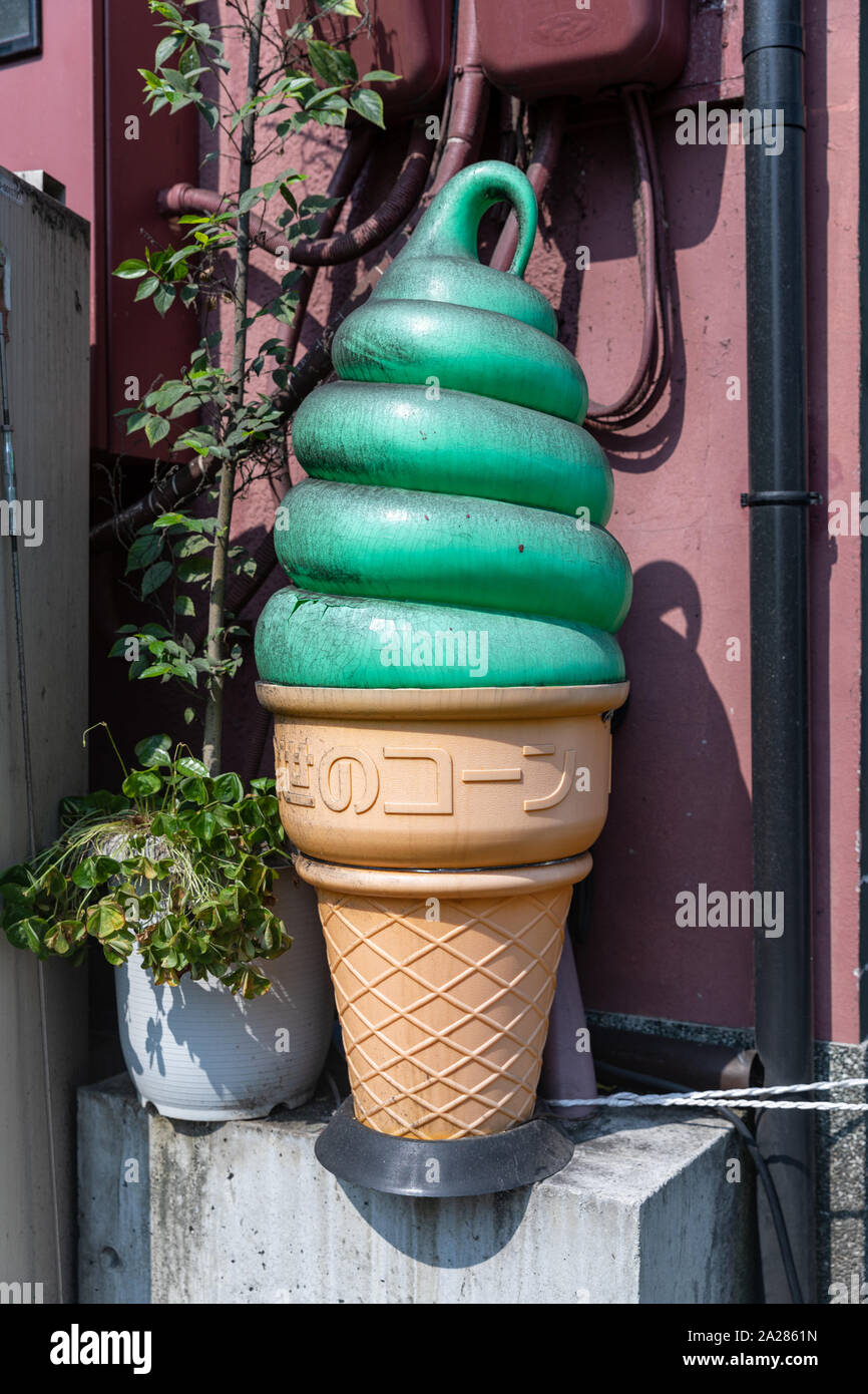Large dirty plastic ice cream cone with green ice cream and Japanese text on the cone; Kyoto, Japan Stock Photo