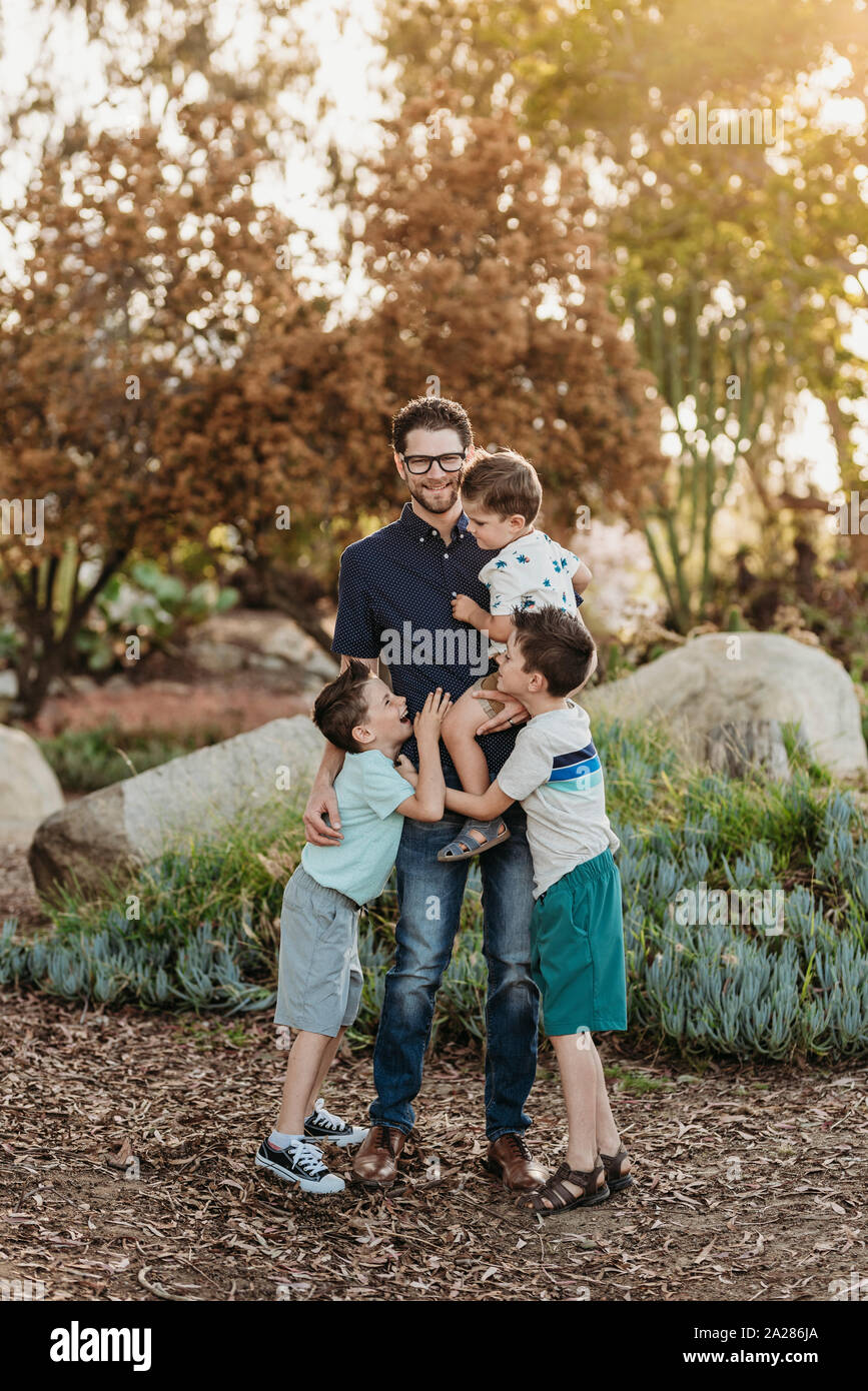 Portrait of dad holding three sons and smiling in sunny cactus garden Stock Photo