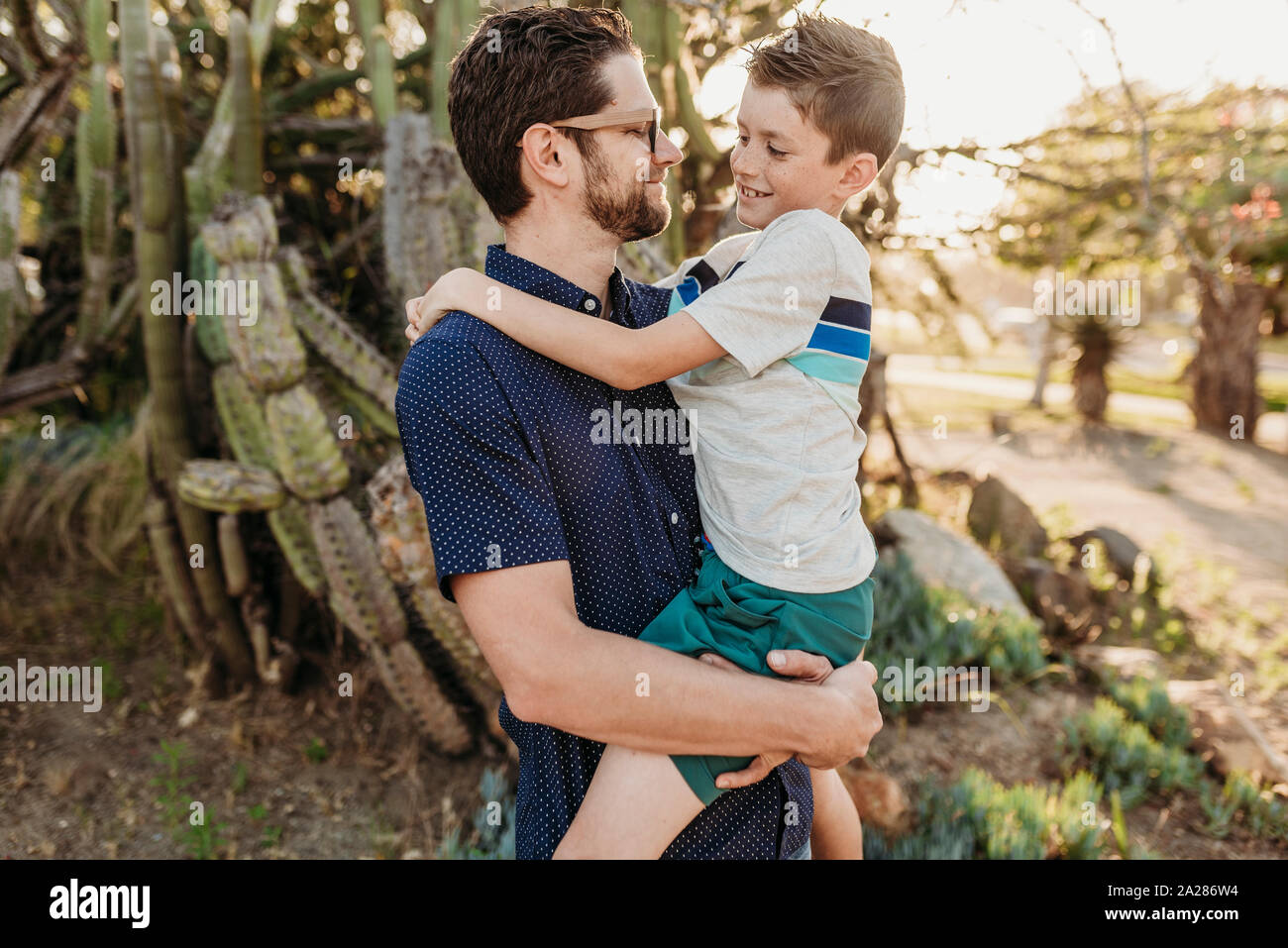 Portrait of father holding older son and smiling at each other Stock Photo