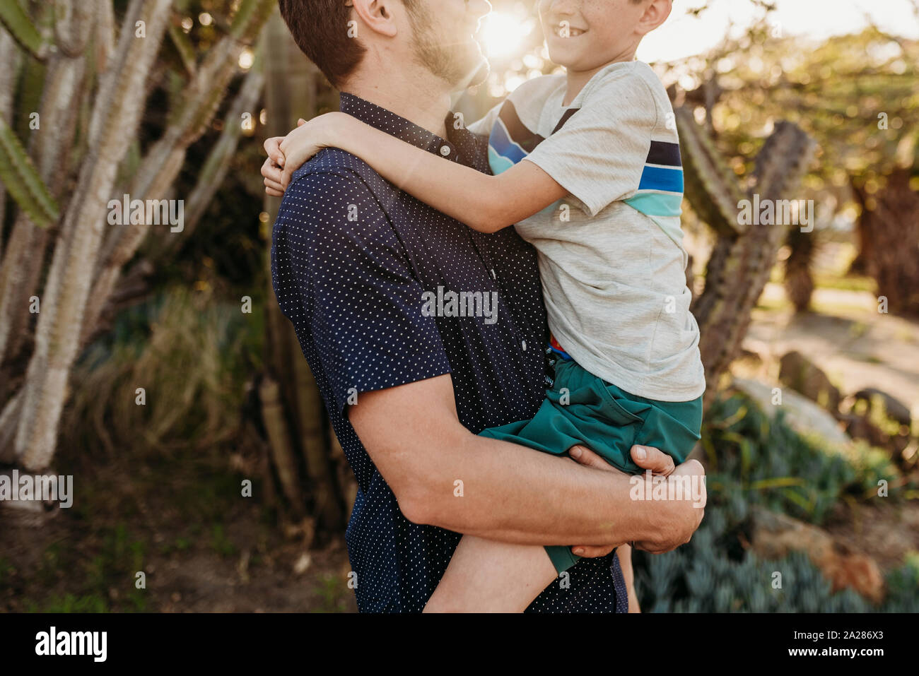 Mid view of father holding older son and smiling at each other Stock Photo