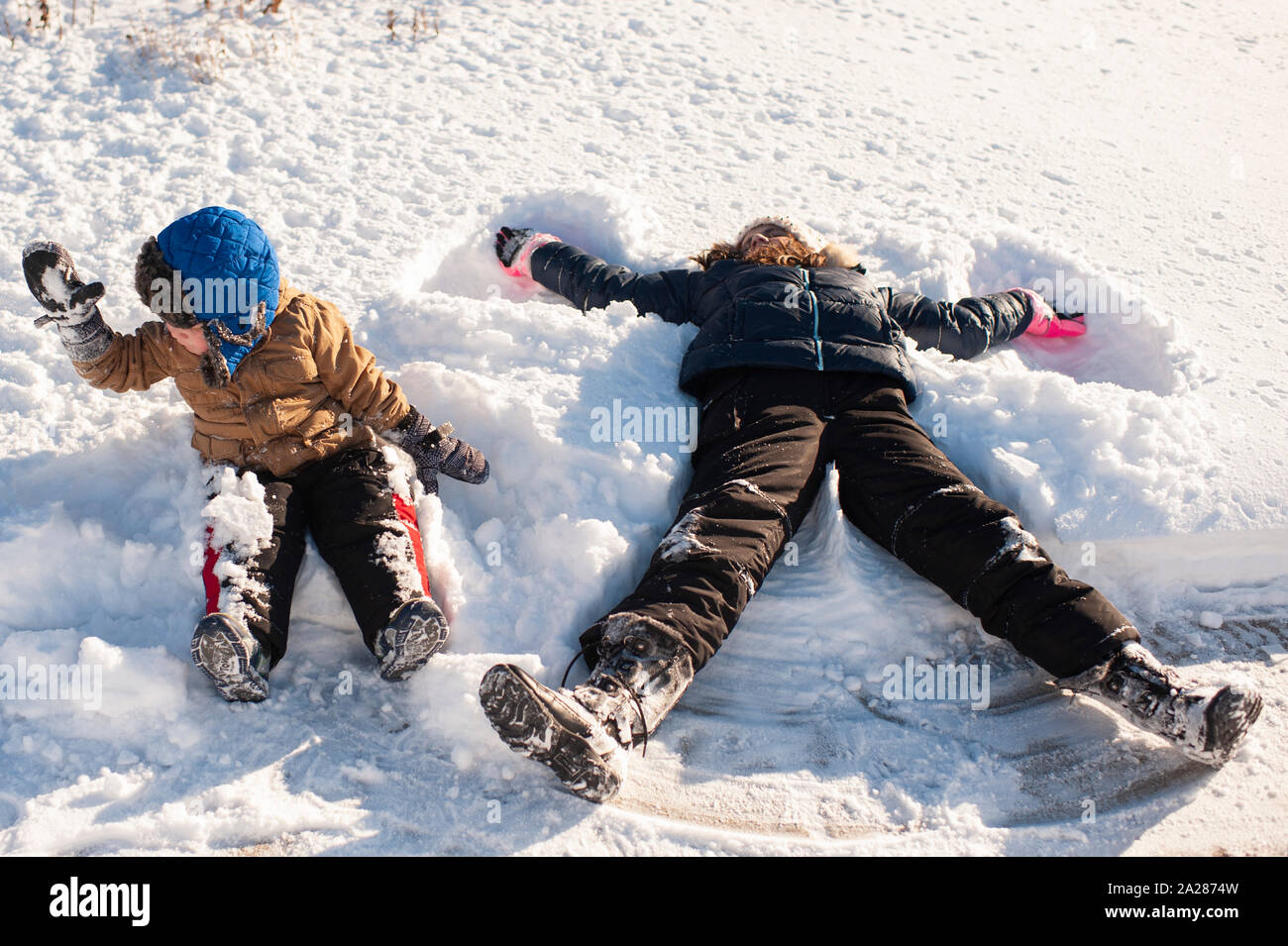 Brother and Sister playing in the snow in front yard Stock Photo