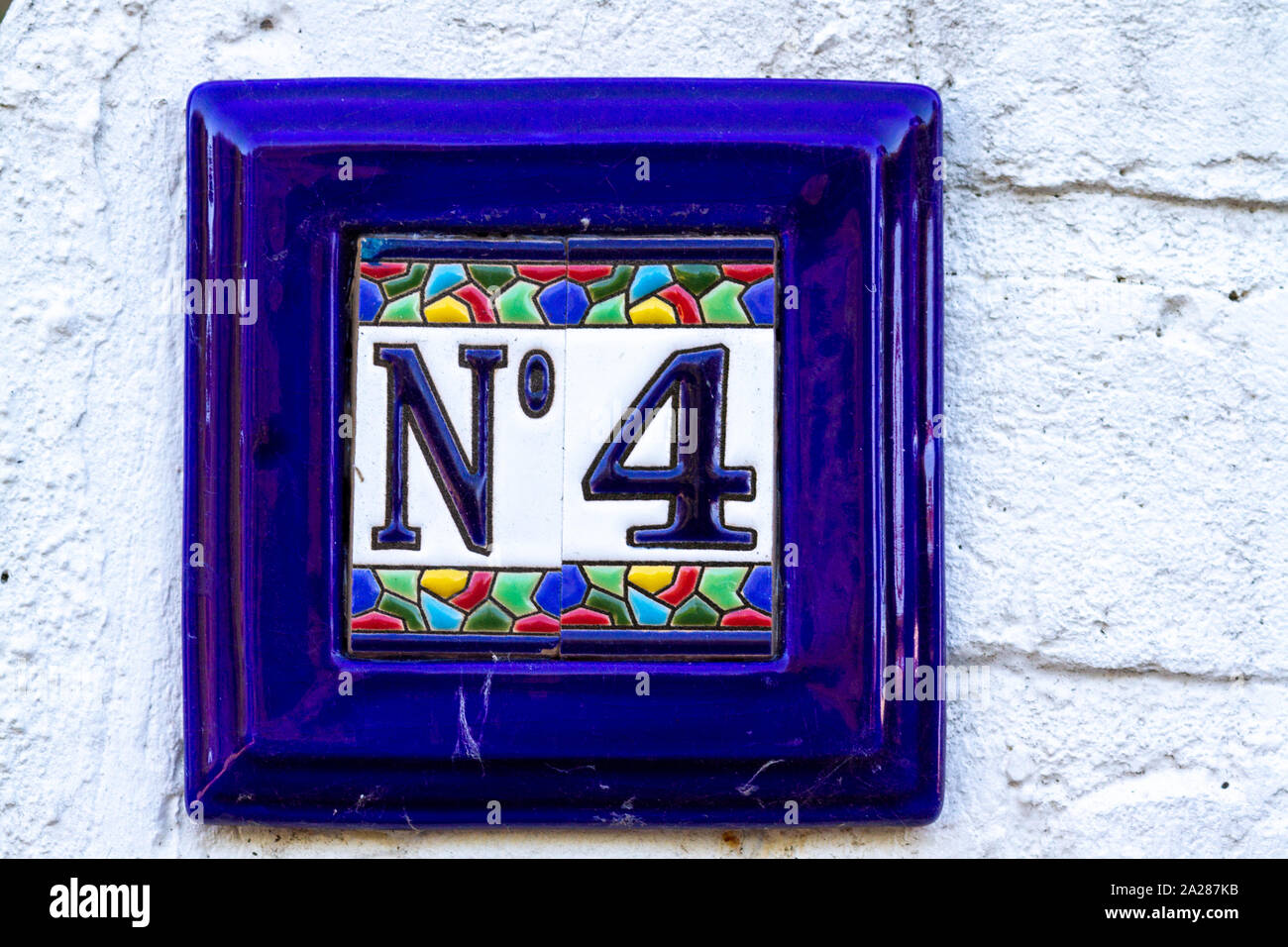 House number 4 on a bright blue tile Stock Photo