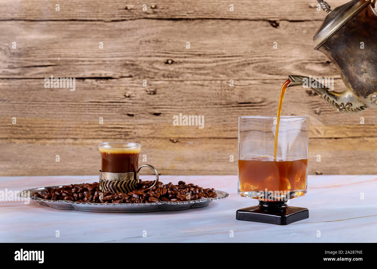 Pouring cold brew iced coffee from french press into the glass Stock