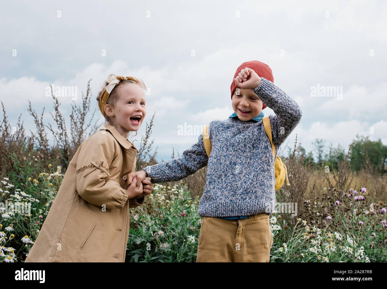 brother and sister holding hands laughing and playing outside Stock Photo