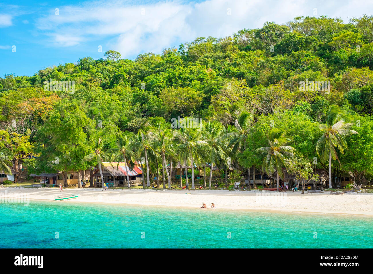 Two people sitting on the white sand beach at Banana Island, Coron