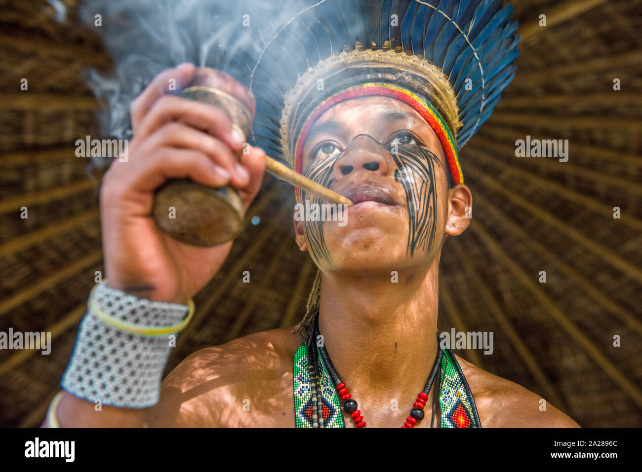 Indigenous Brazilian smokes traditional pipe at the village Stock Photo