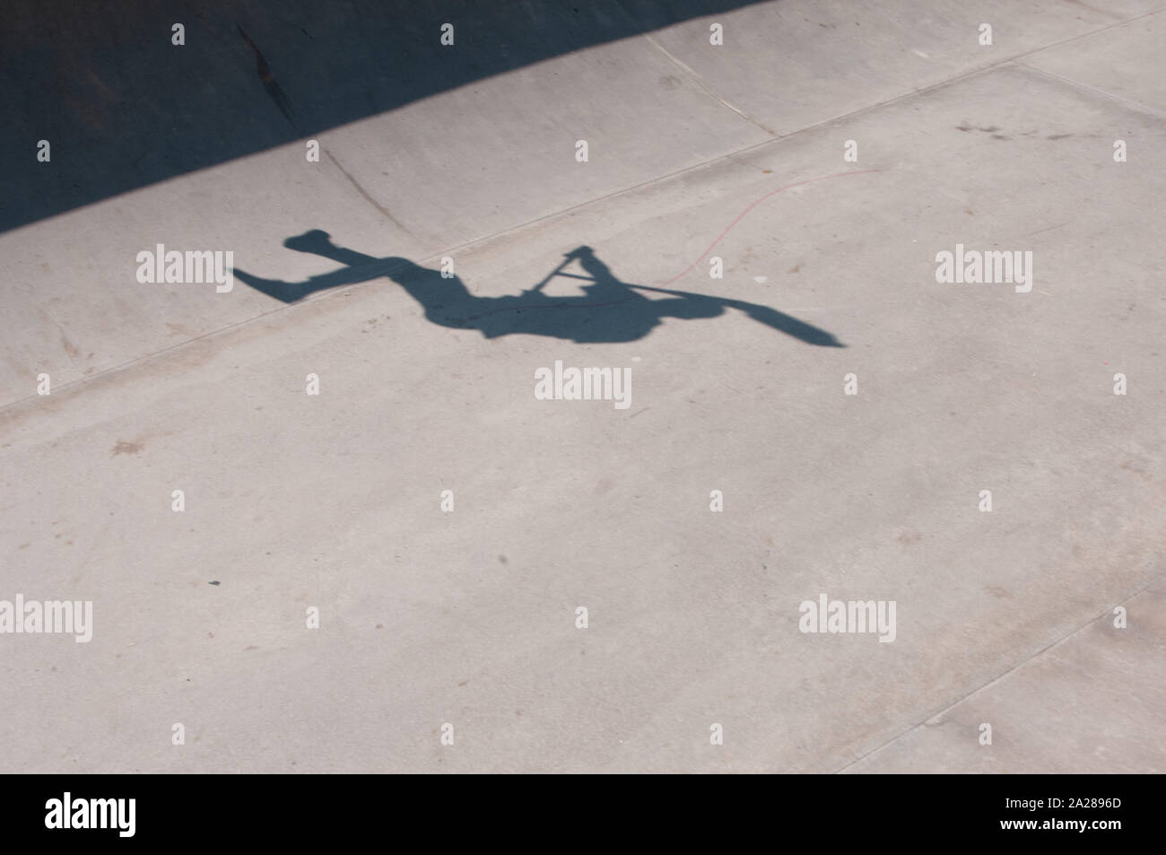 shadow of a boy with a scooter at skateboard park Stock Photo