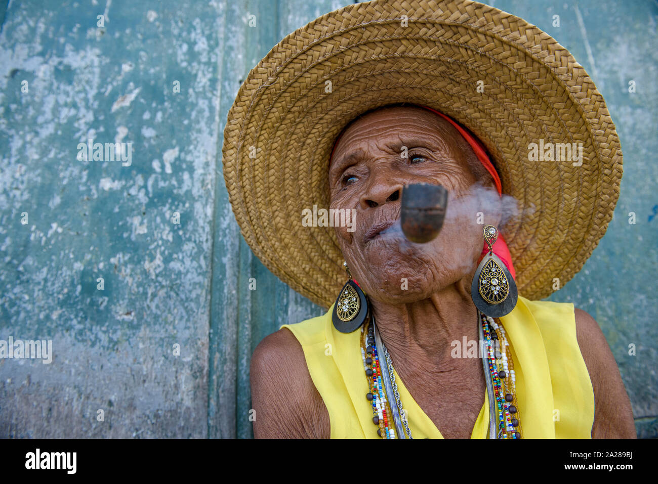 Senior Afro-Brazilian woman smoking pipe wearing straw hat Stock Photo