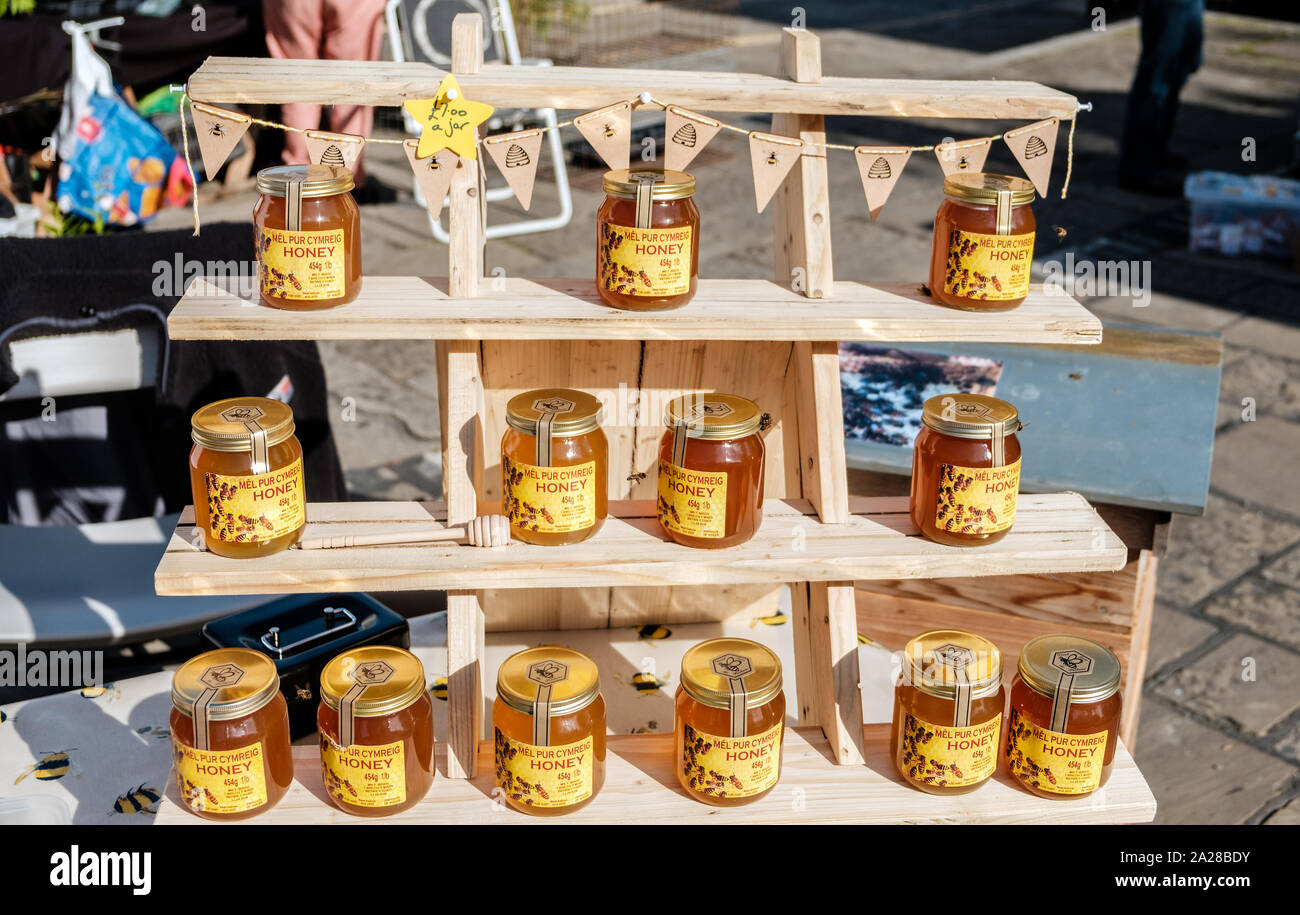 Conwy, Wales UK- September, 13 2019 MEL PUR CYMREIG honey surrounded by hungry bees produce of Wales displayed on wooden shelving and being sold at Co Stock Photo