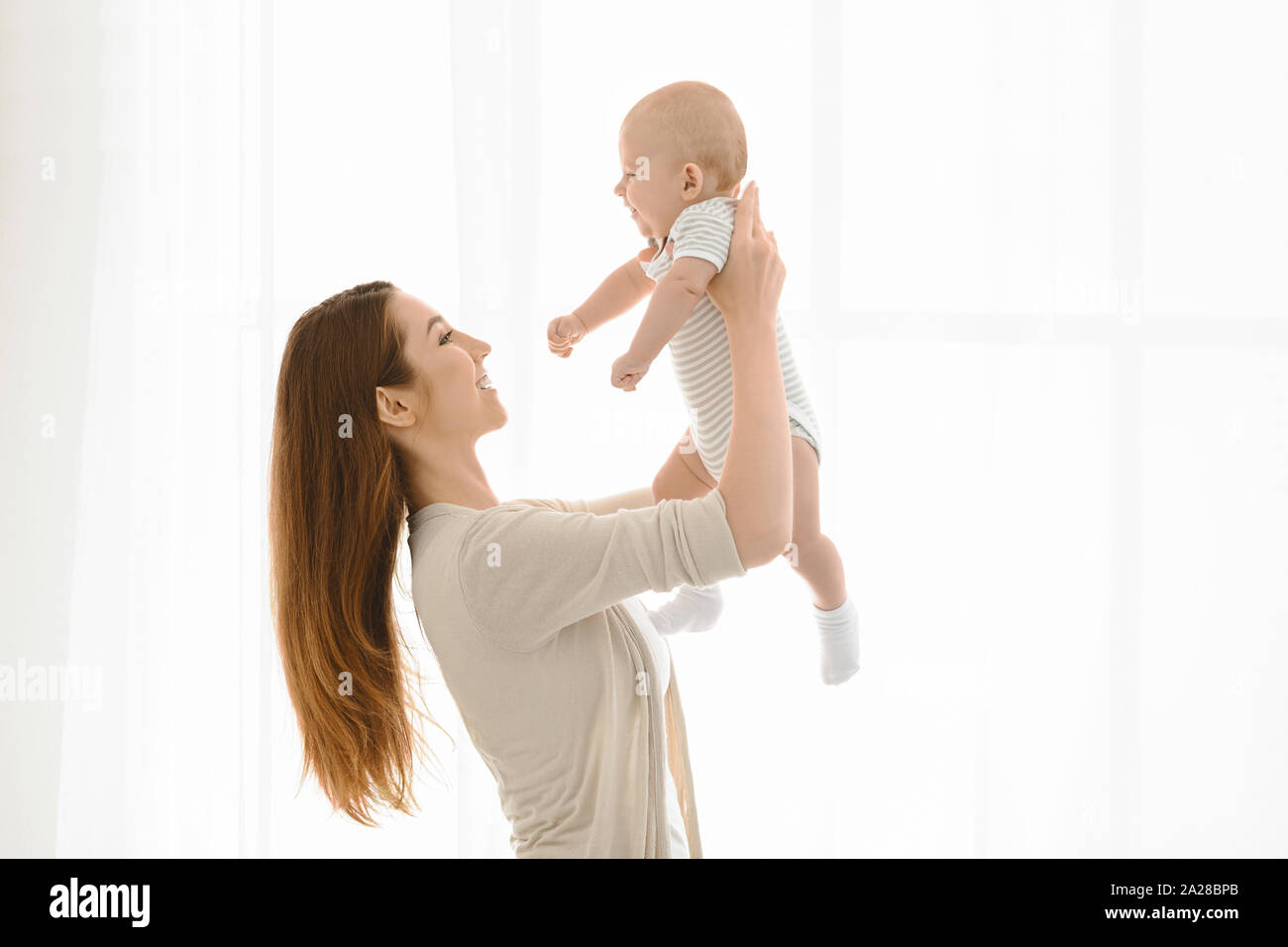 Young woman lifting her adorable newborn baby up in air Stock Photo Alamy