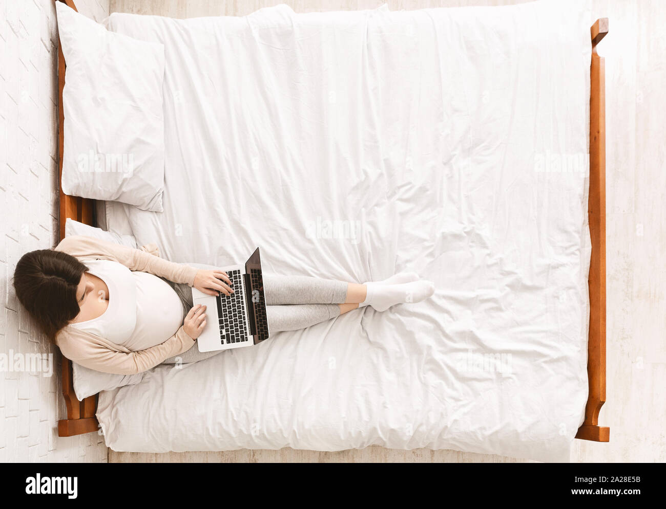 Pregnant woman working on laptop, sitting on bed Stock Photo Alamy