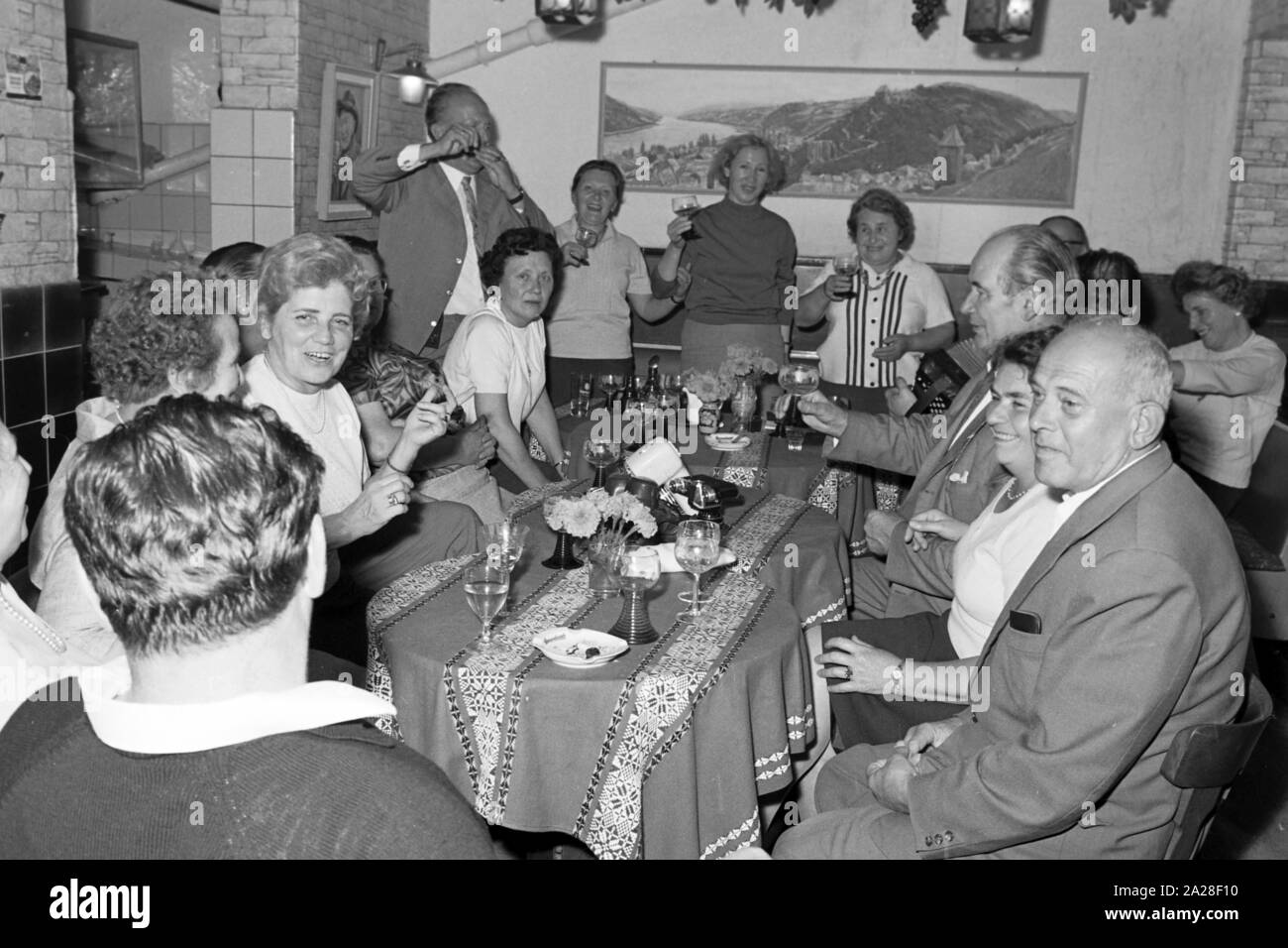 Menschen feiern in geselliger Runde in Bacharach, Deutschland 1968. People having a feast at Bacharach, Germany 1968. Stock Photo