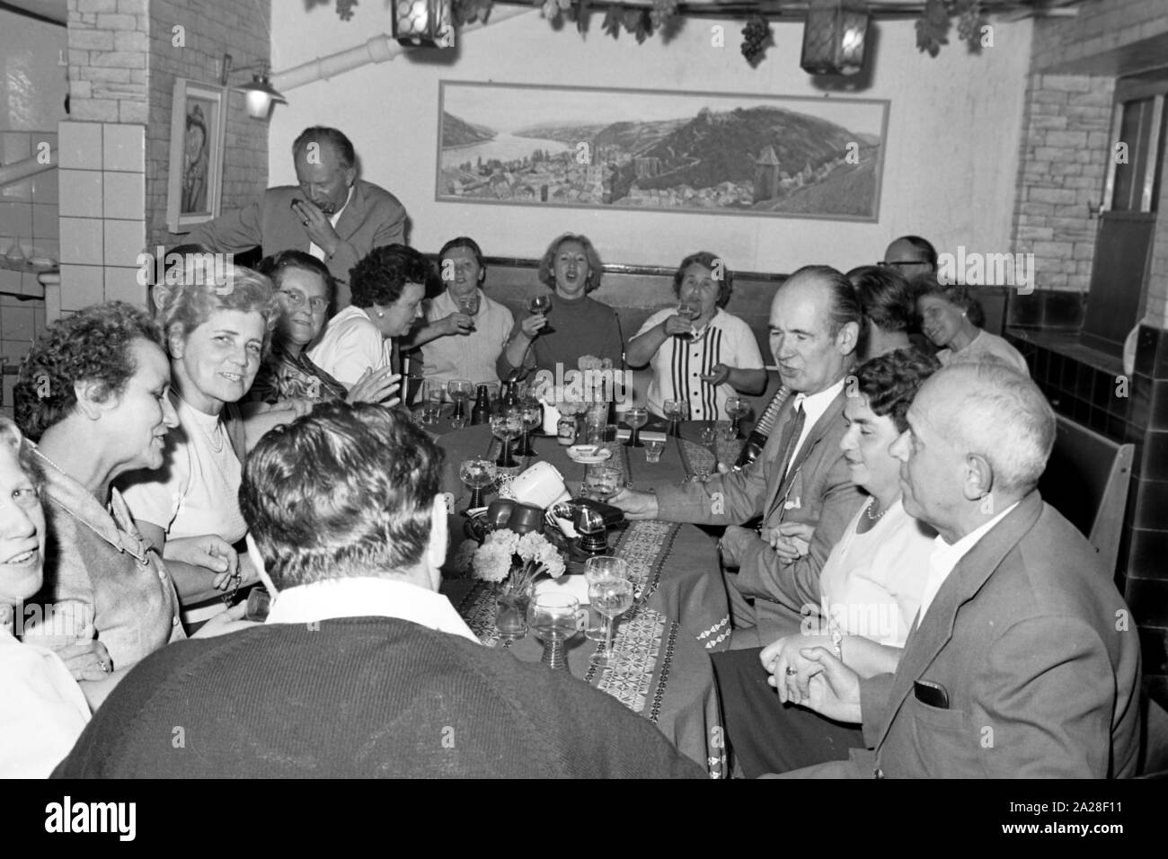 Menschen feiern in geselliger Runde in Bacharach, Deutschland 1968. People having a feast at Bacharach, Germany 1968. Stock Photo