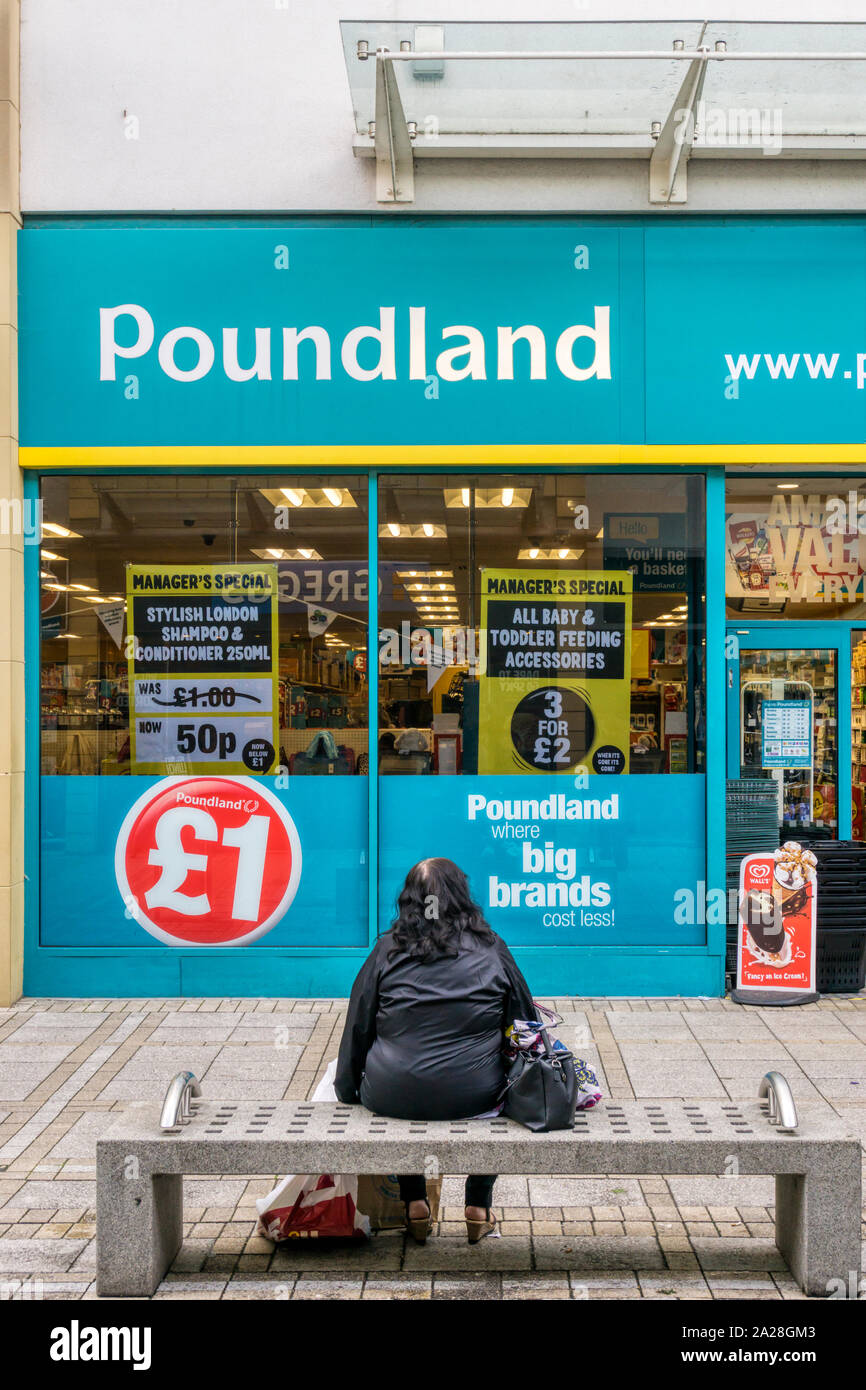 A woman having a rest from shopping in front of Poundland shop in King's Lynn. Stock Photo