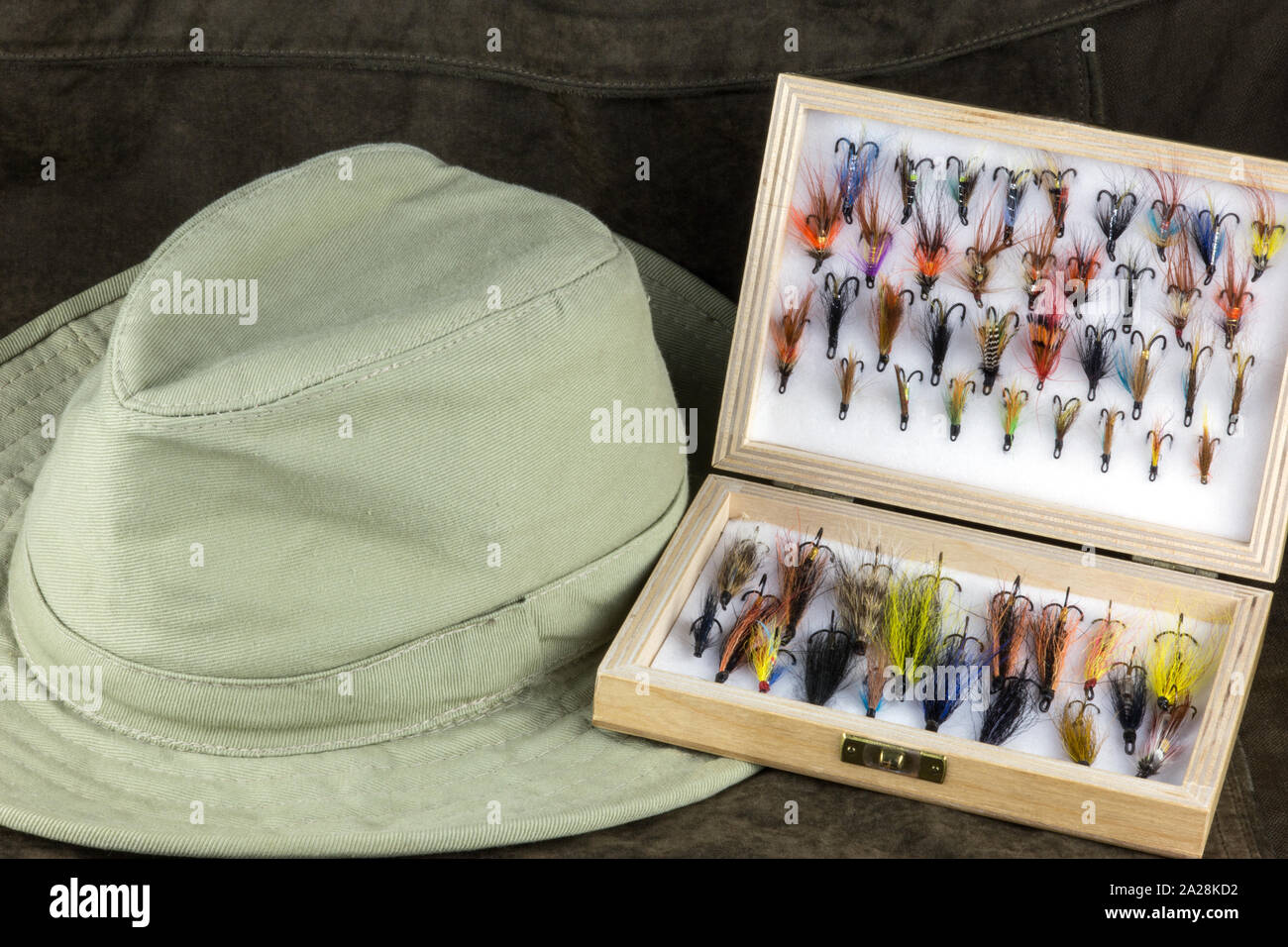 https://c8.alamy.com/comp/2A28KD2/fishing-flies-in-wooden-fly-box-with-hat-on-an-outdoor-coat-2A28KD2.jpg