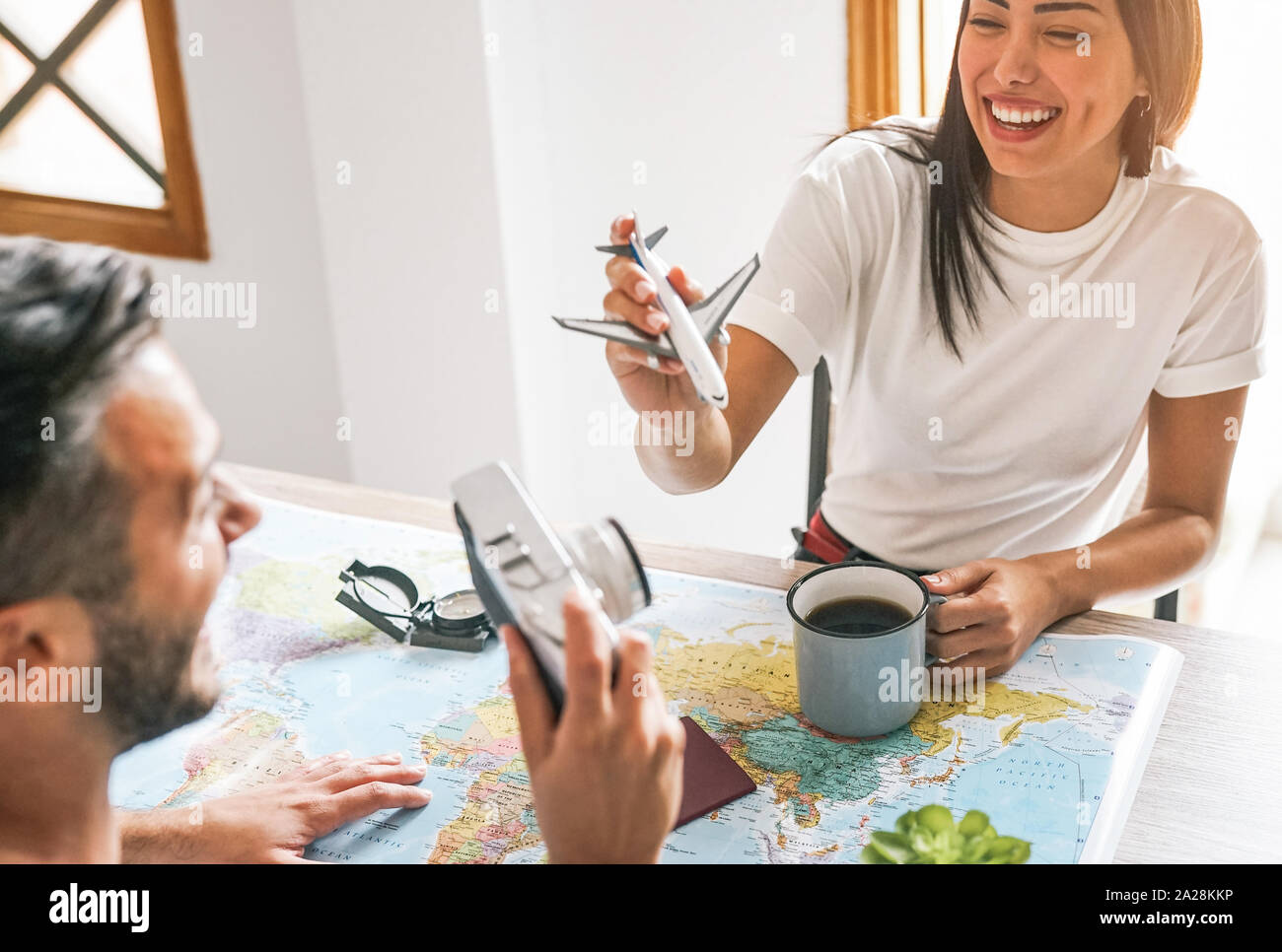 Happy couple having fun planning next world tour together - Young people getting ready for next trip using a travel map Stock Photo
