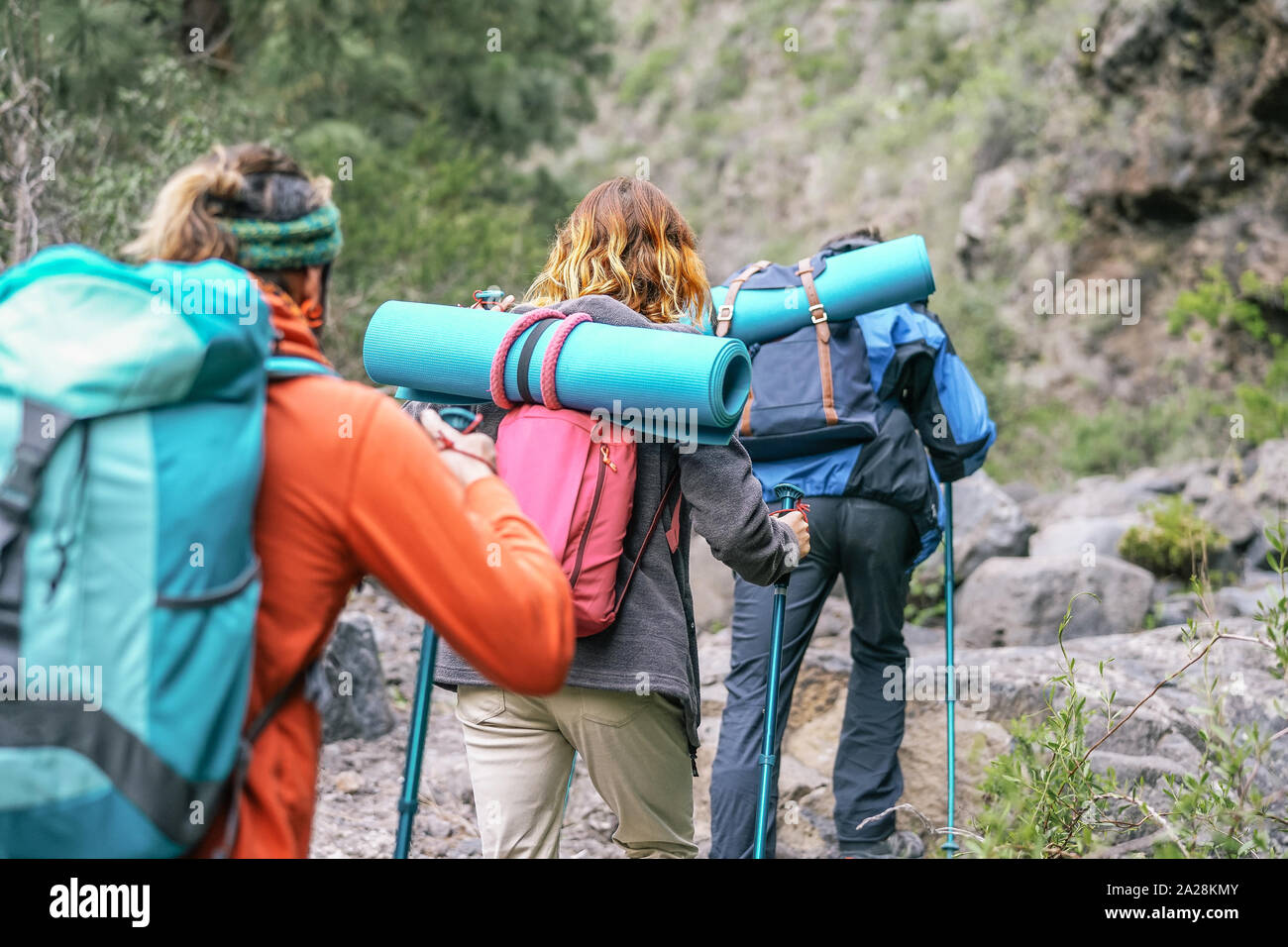 Group of people with backpacks doing trekking excursion on mountain - Young tourists walking and exploring the nature Stock Photo