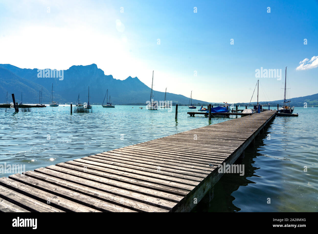 Mondsee Lake in Austria with pier, boats and mountains at summer Stock Photo
