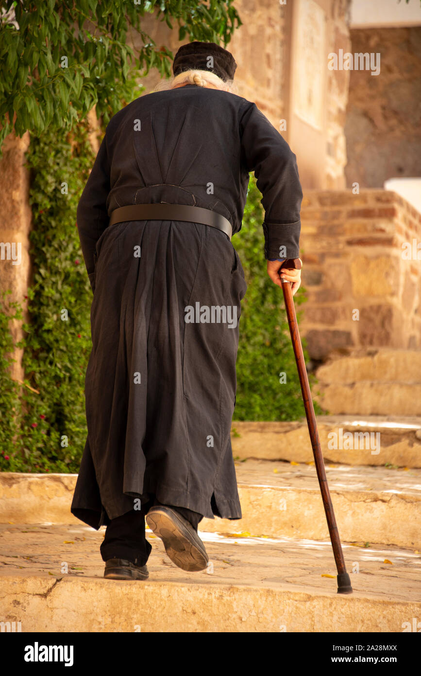 A monk from Saint Catherine's Monastery of Mount Sinai, walking with a cain up the steps of the historical site Stock Photo
