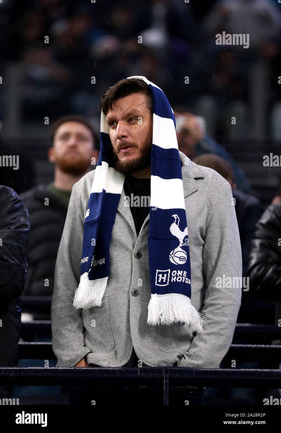 A Tottenham Hotspur fan in the stands shelters under a scarf from the rain during the UEFA Champions League match at Tottenham Hotspur Stadium London Stock Photo Alamy