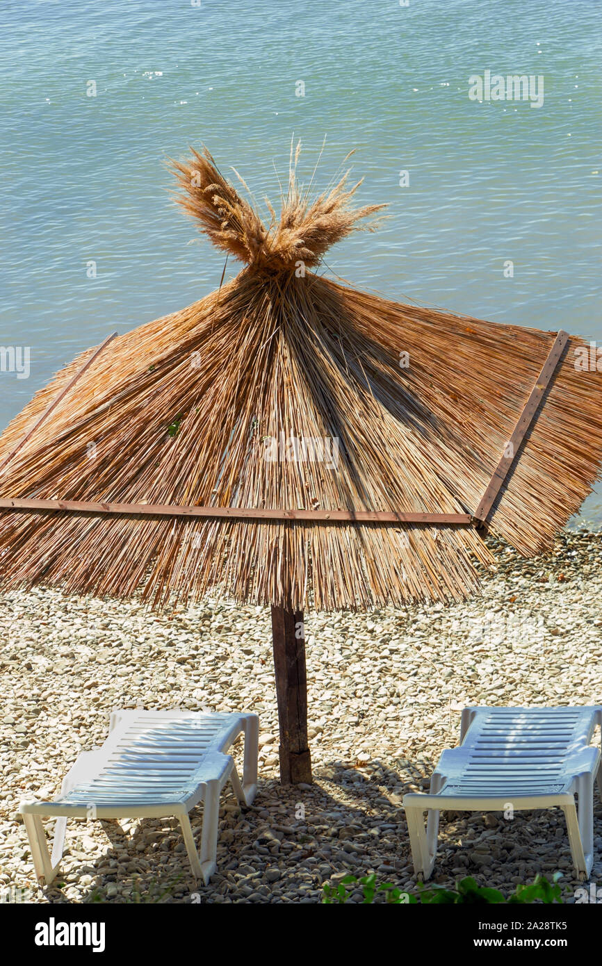 Two deck chairs and umbrella on a beach. Vacation background. Sunny day. Stock Photo
