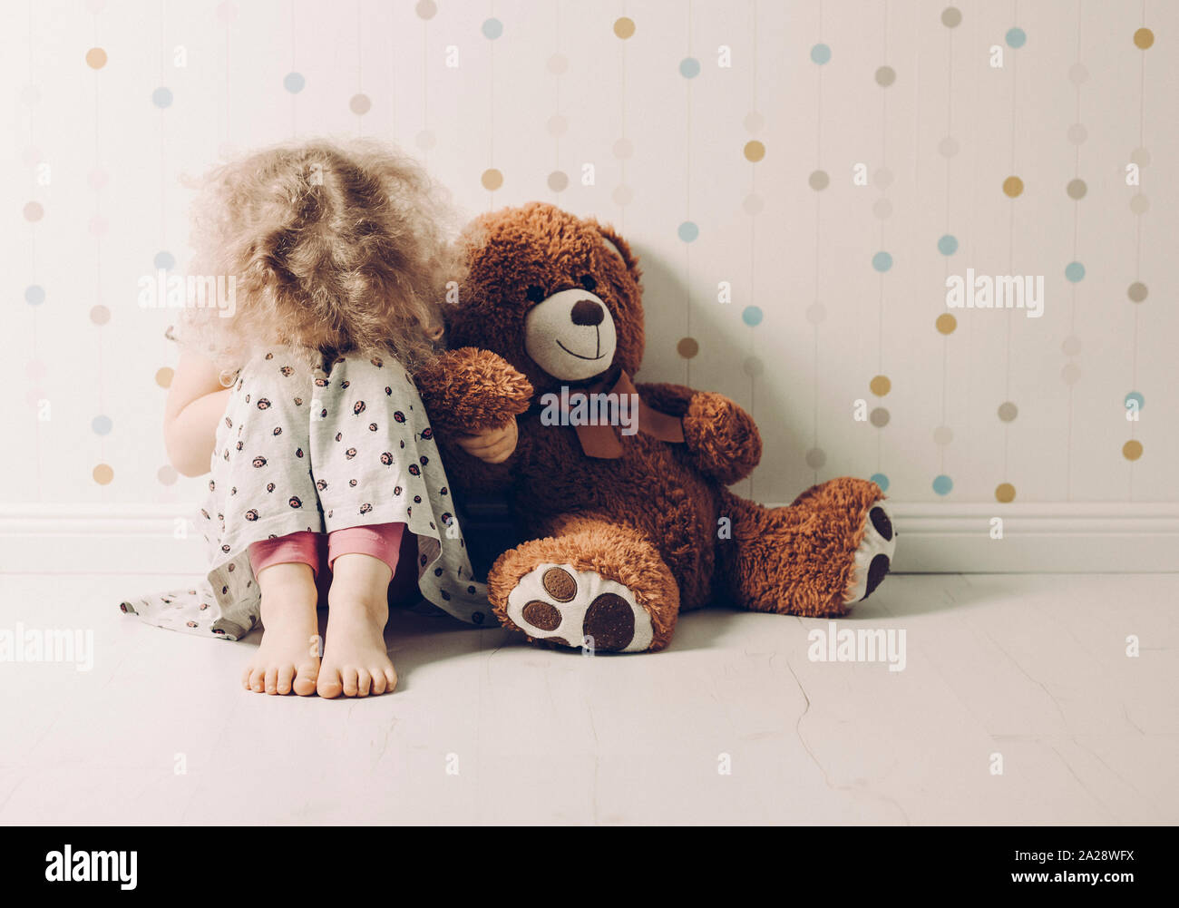 Little curly haired girl crying in her room. Little girl needs attention. Stock Photo