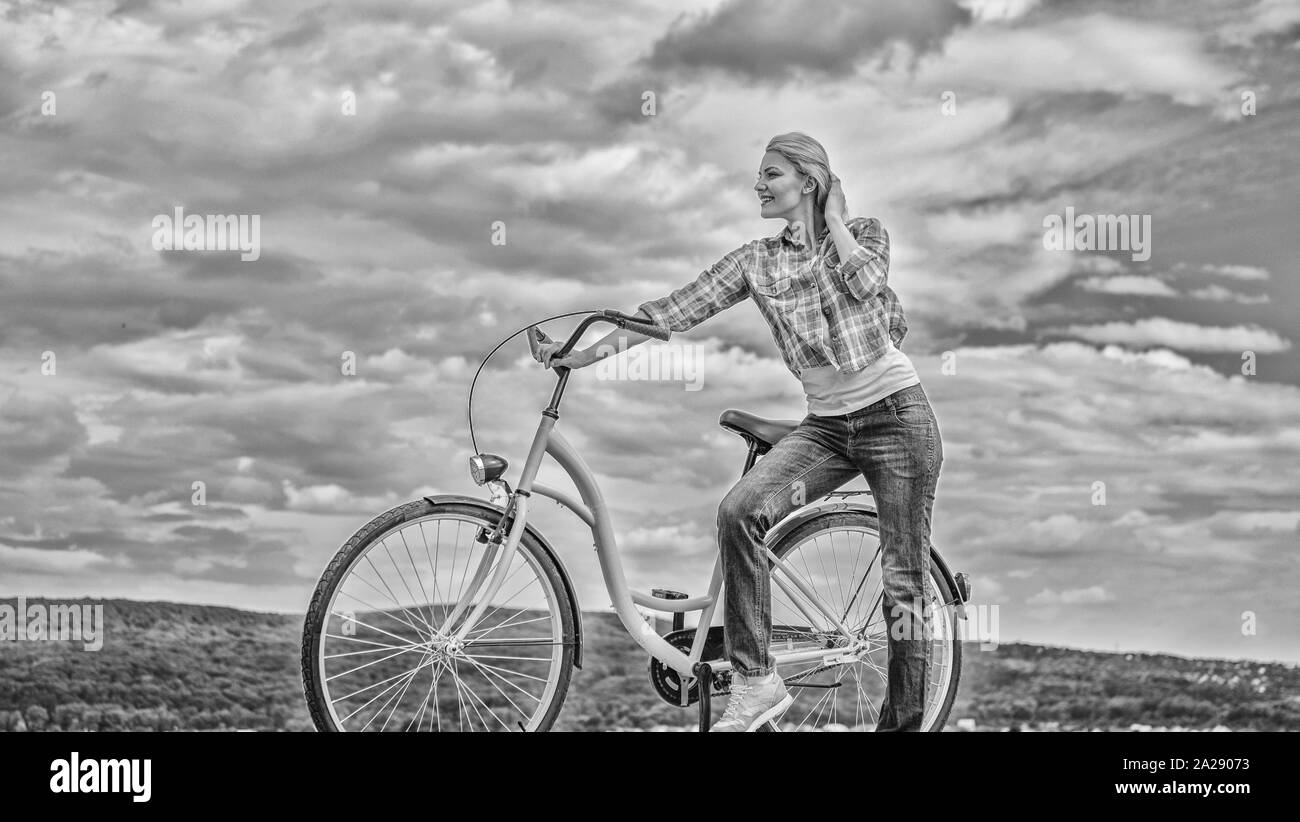 Health benefits of cycling. Woman rides bicycle sky background