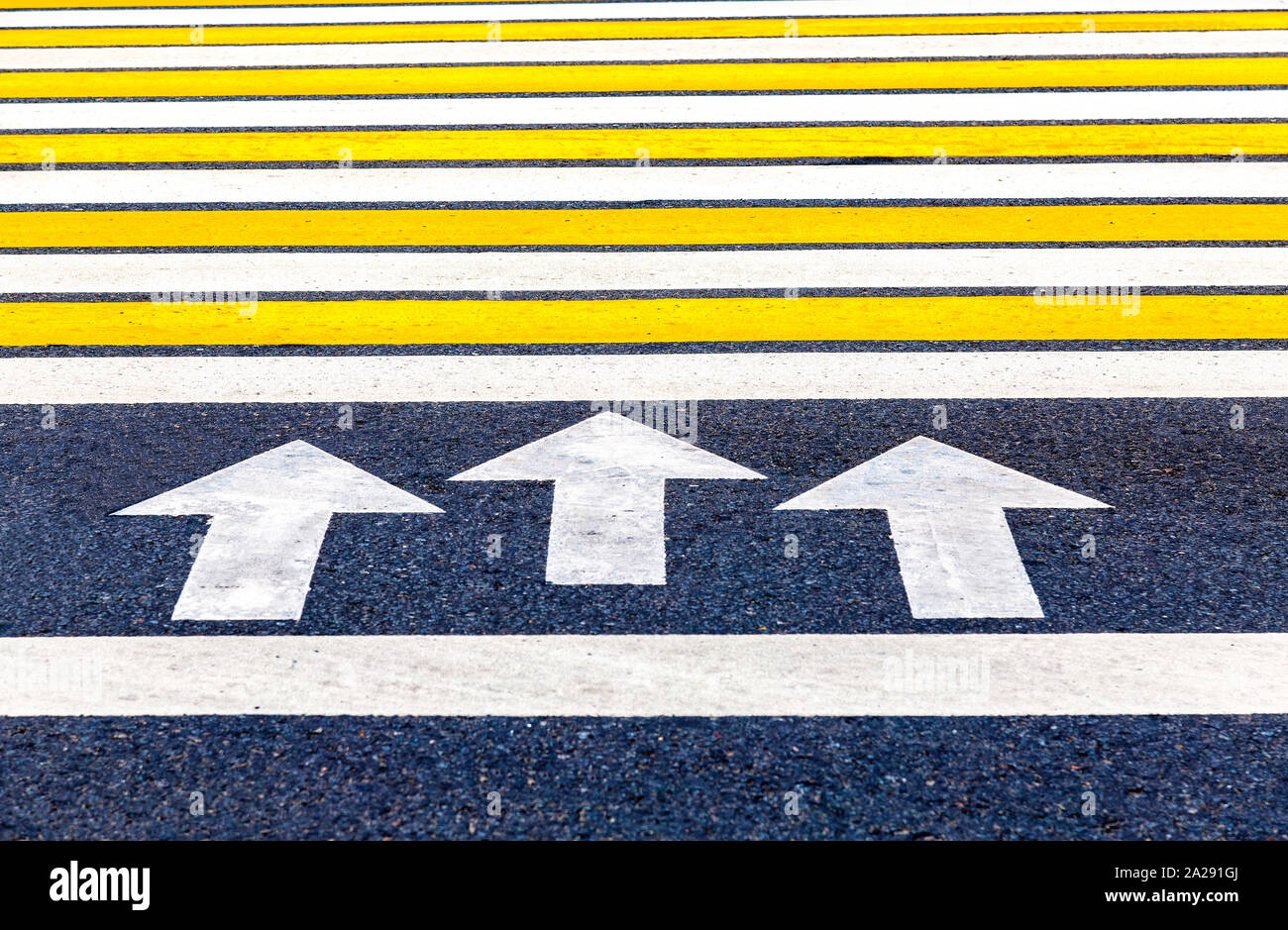 Pedestrian crossing with arrows, white and yellow stripes close up ...