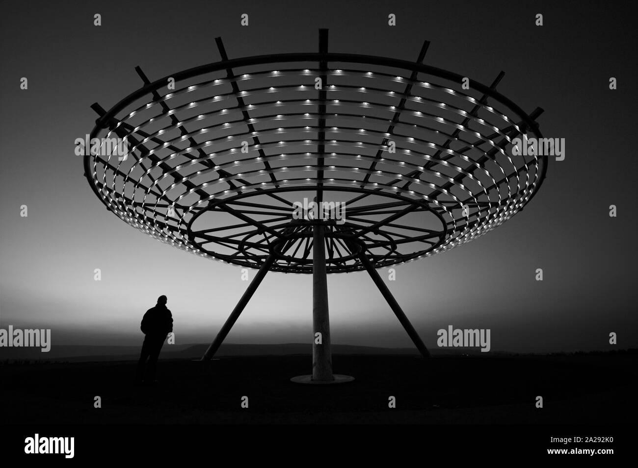 Sculpture, man standing under the Halo lit up at night, Panopticon ...