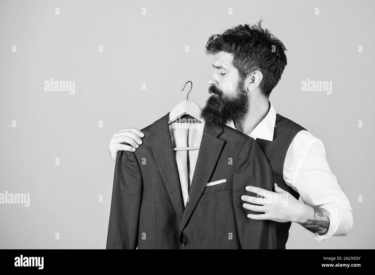 When the invite says formal. Bearded man at formal wear boutique. Hipster choosing formal suit jacket in wardrobe. Classy formal look of fashion model. Stock Photo