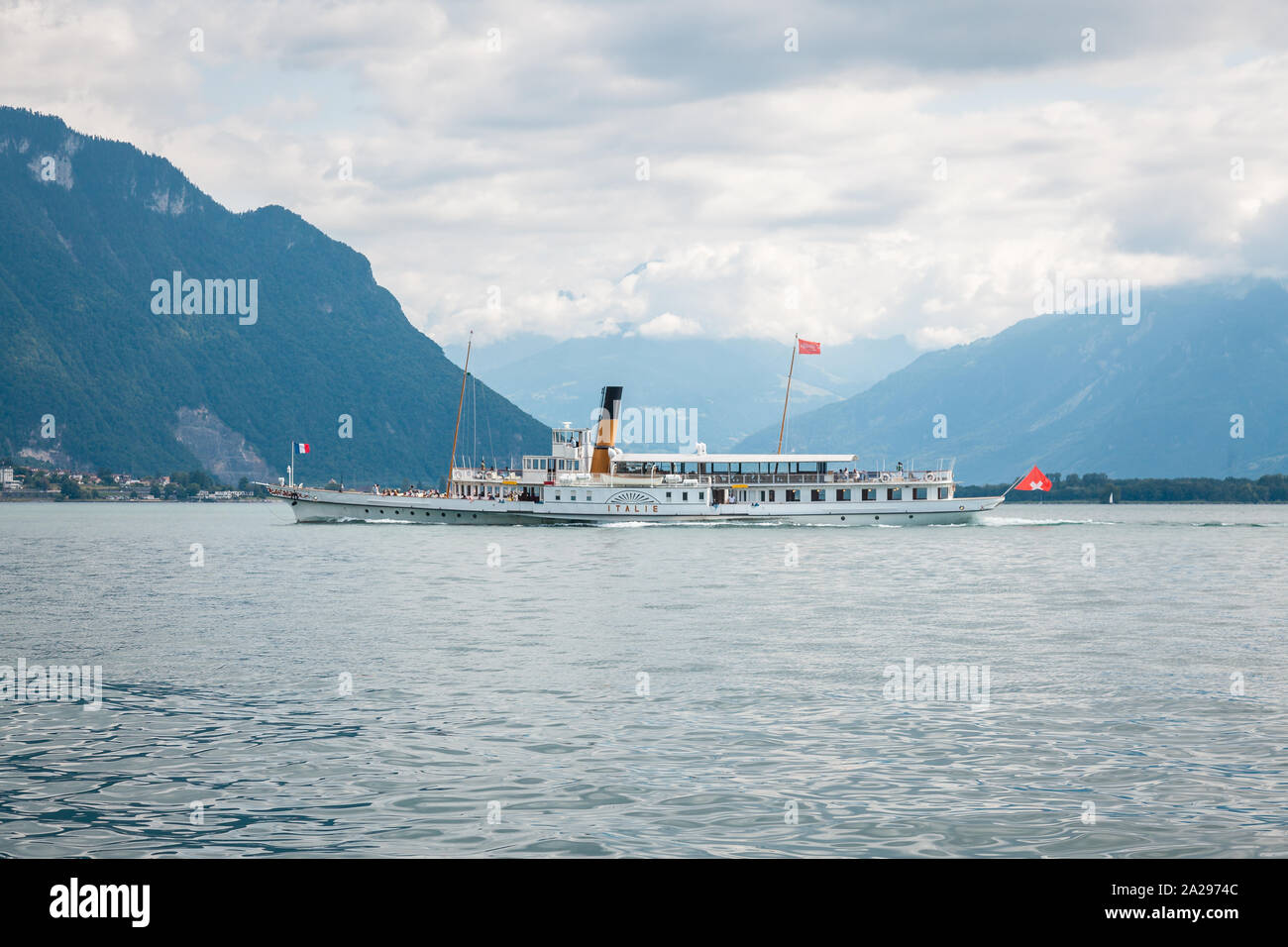 Traditional passenger paddle boat named Italie cruising on the Lake Geneva (Lac Leman) along Swiss shore with Alps mountains on the background Stock Photo