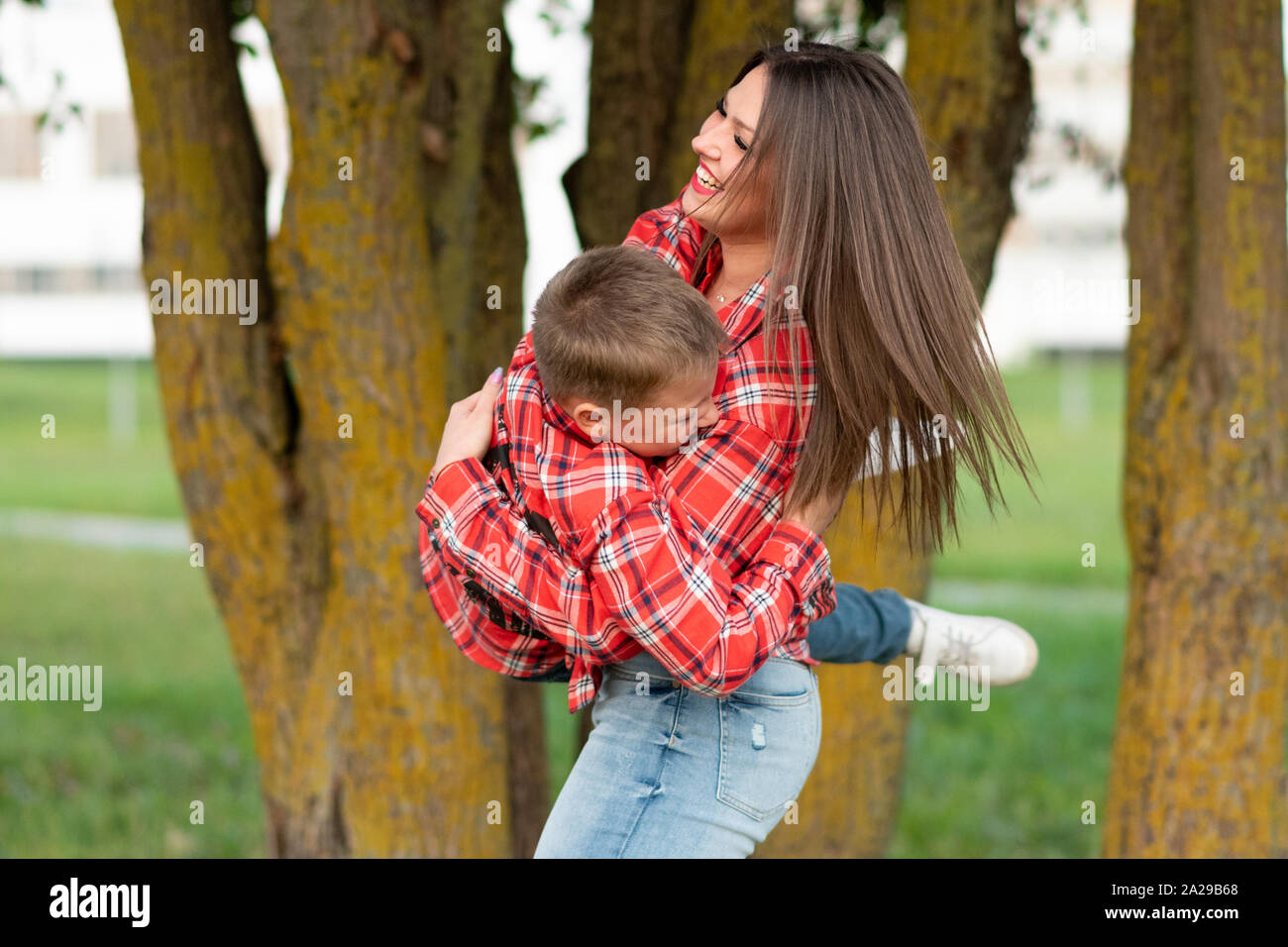 Mom, laughing cheerfully, circling her son, holding him in her arms. Stock Photo