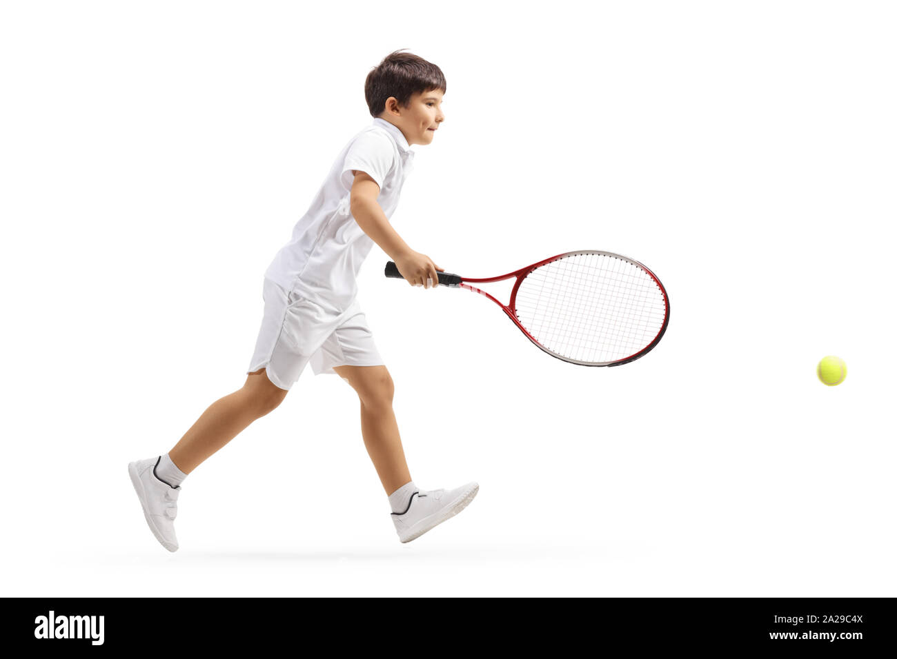 Full length profile shot of a boy running to hit a tennis ball isolated on white background Stock Photo