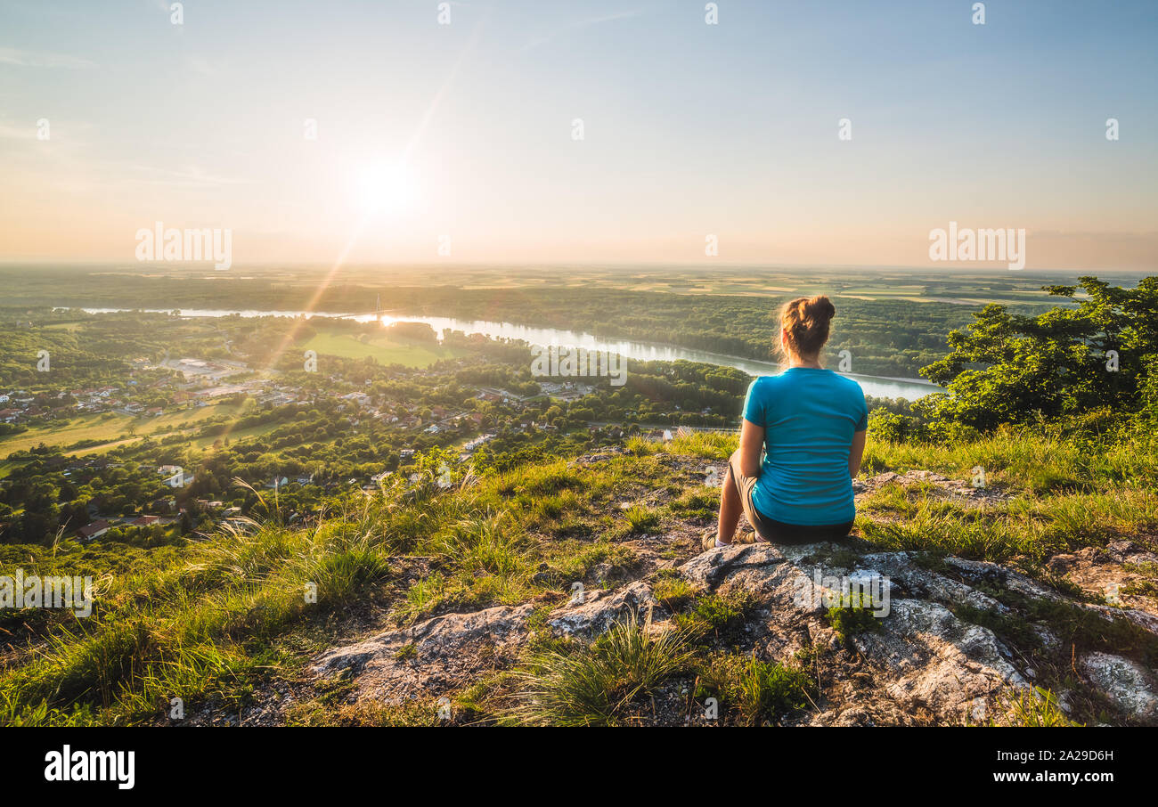 A Girl Sits on the Edge of the Cliff and Looking at the Sunset and the ...
