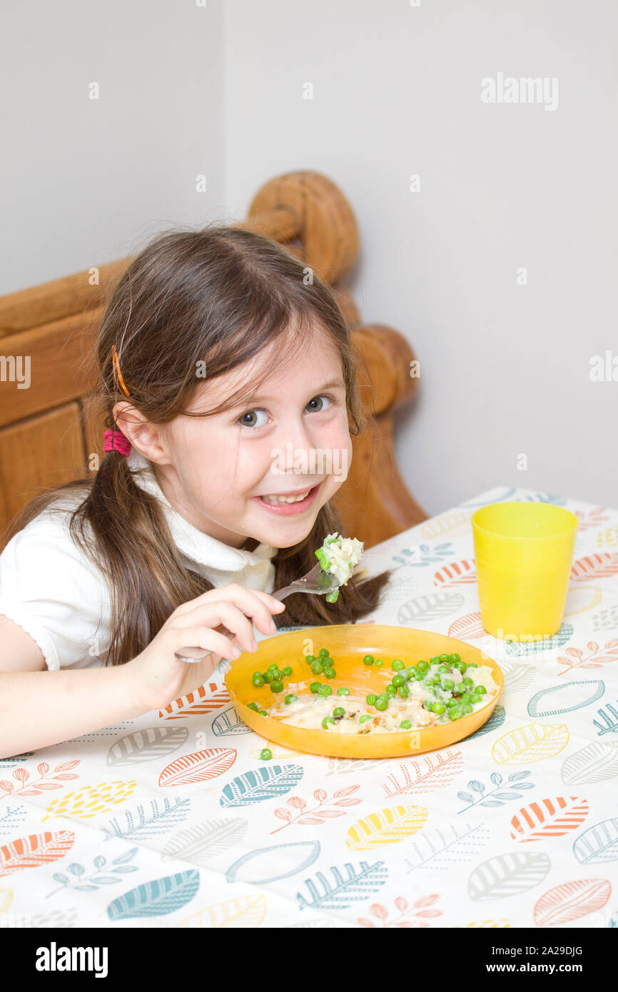 Happy 6 year old eating fish pie at the dinner table Stock Photo Alamy