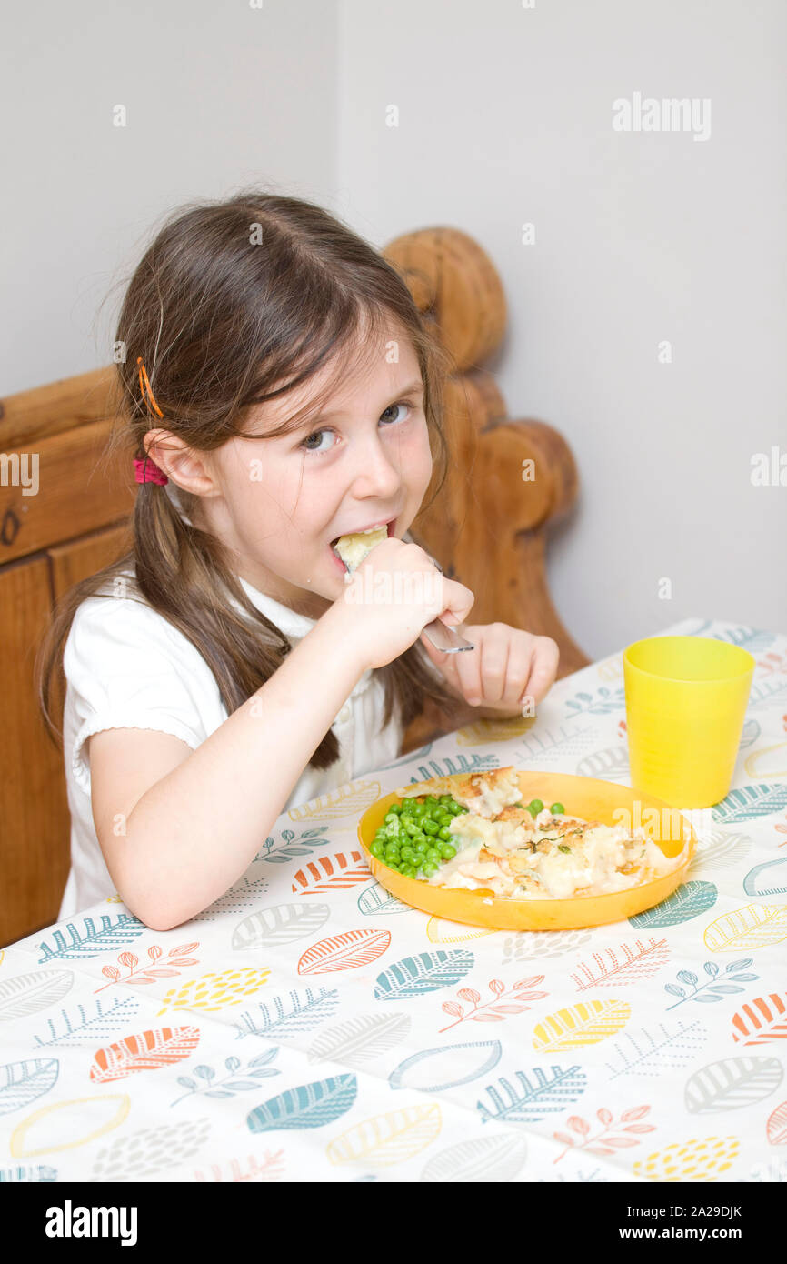 6 year old girl eating fish pie at the dinner table Stock Photo