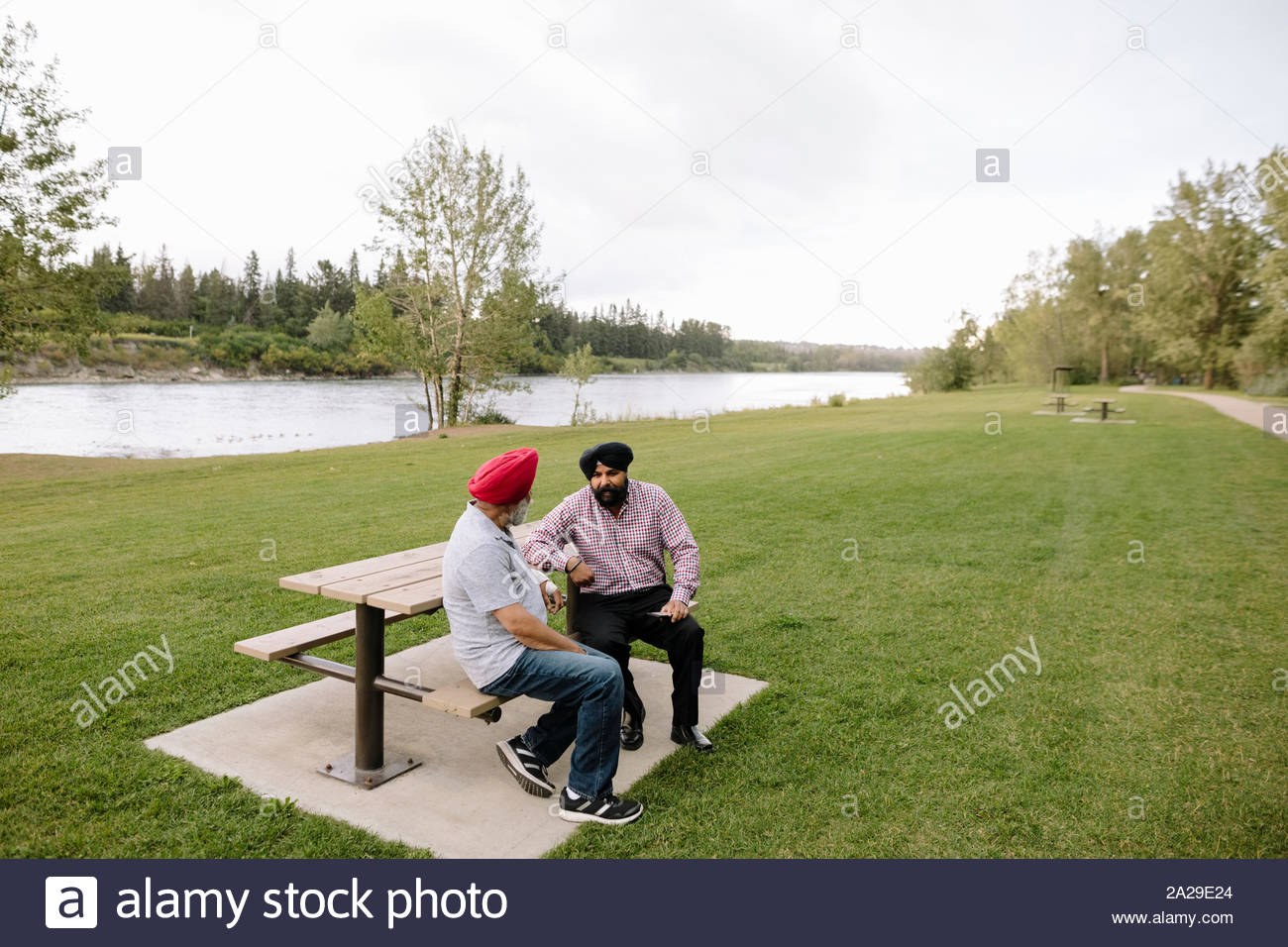 Mature Indian men on park bench talking Stock Photo