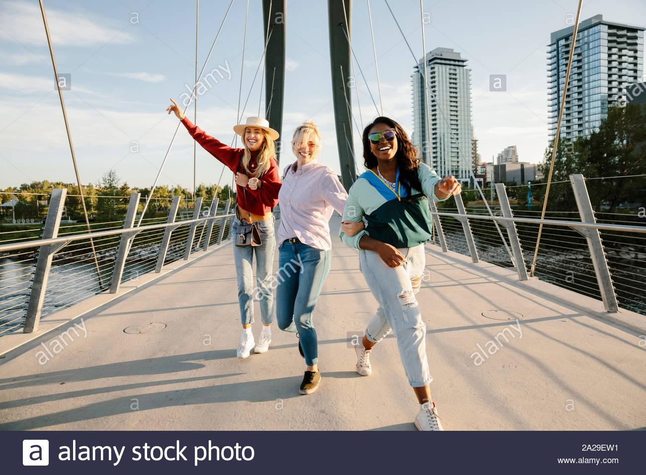 Portrait playful, carefree young women friends on sunny, urban bridge Stock Photo