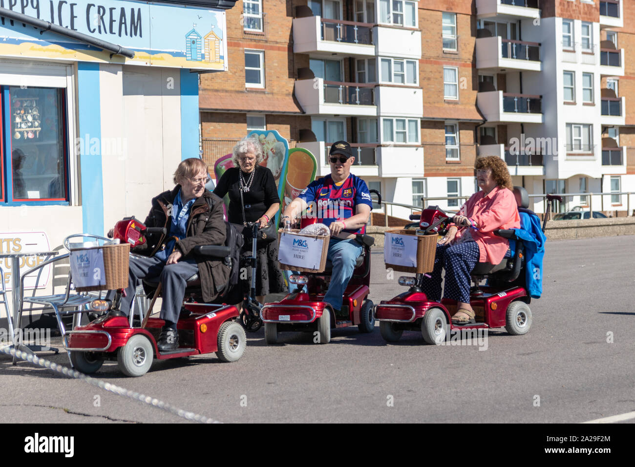 People of various ages on mobility scooters outside a seaside cafe, People with disabilities/disabled Stock Photo