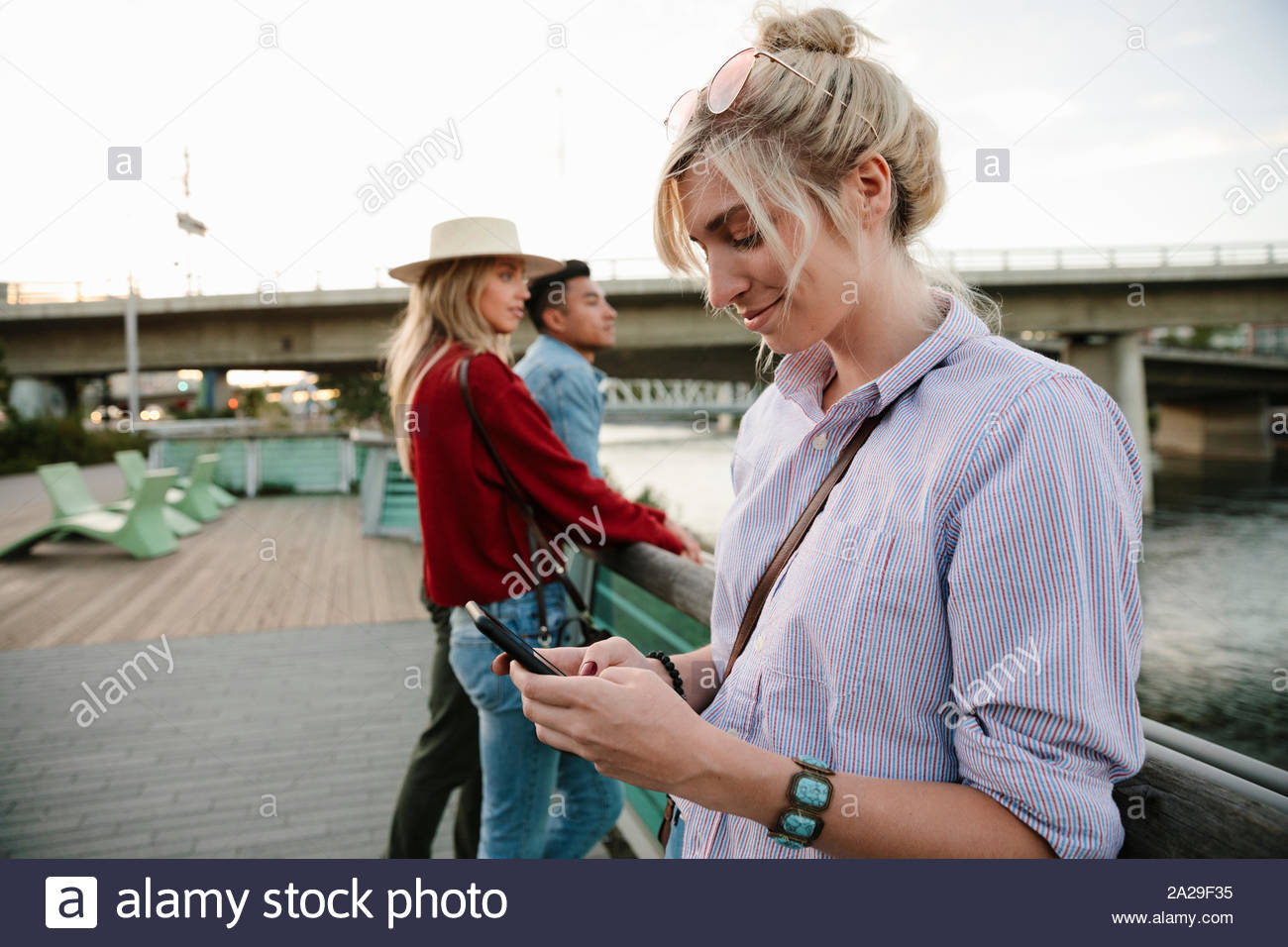 Young woman using smart phone at urban waterfront Stock Photo