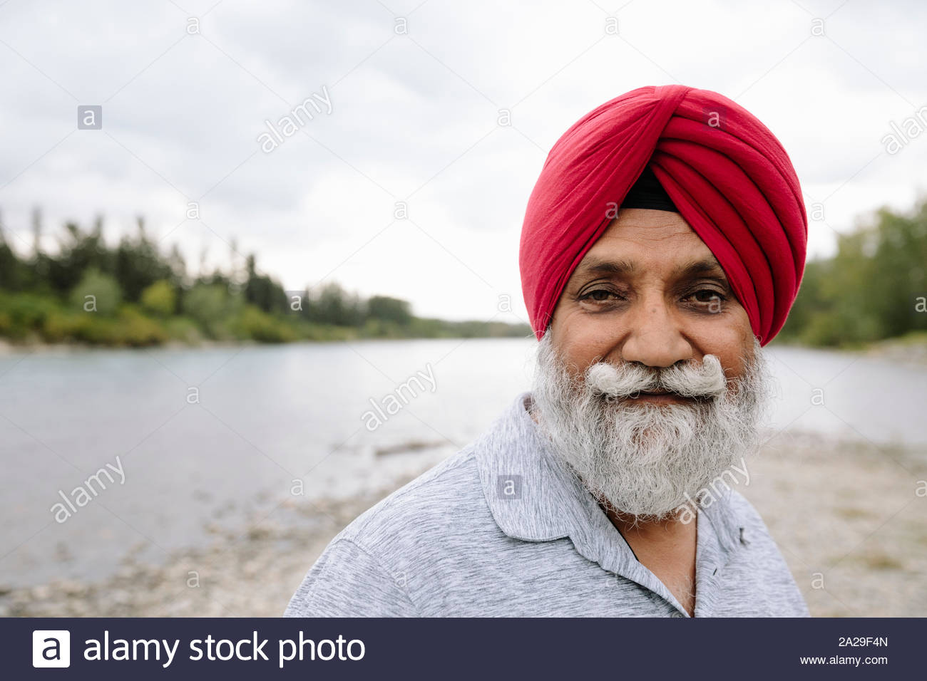 Portrait of Indian man wearing red turban on lakeshore Stock Photo