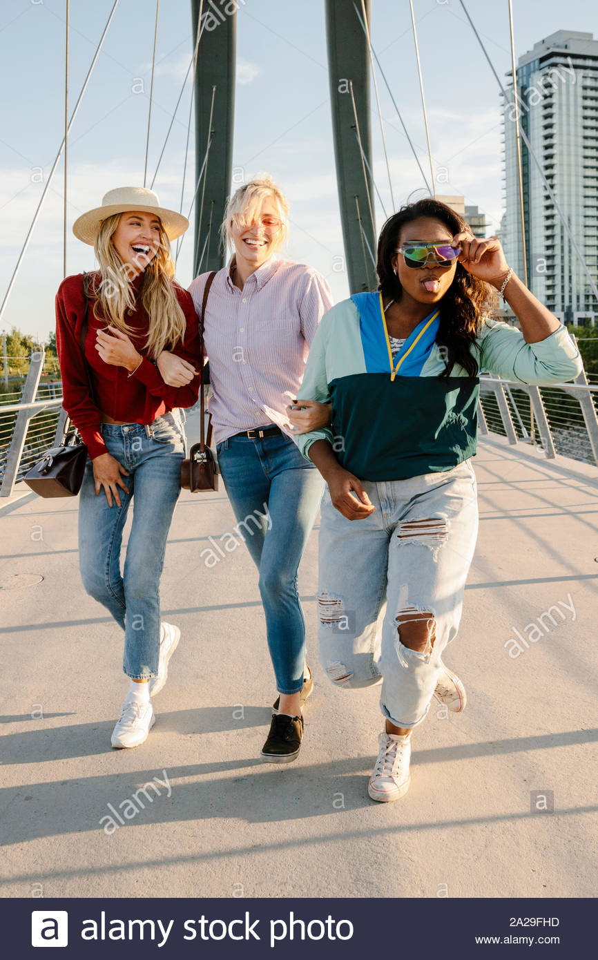 Portrait confident, playful young women friends on sunny, urban bridge Stock Photo