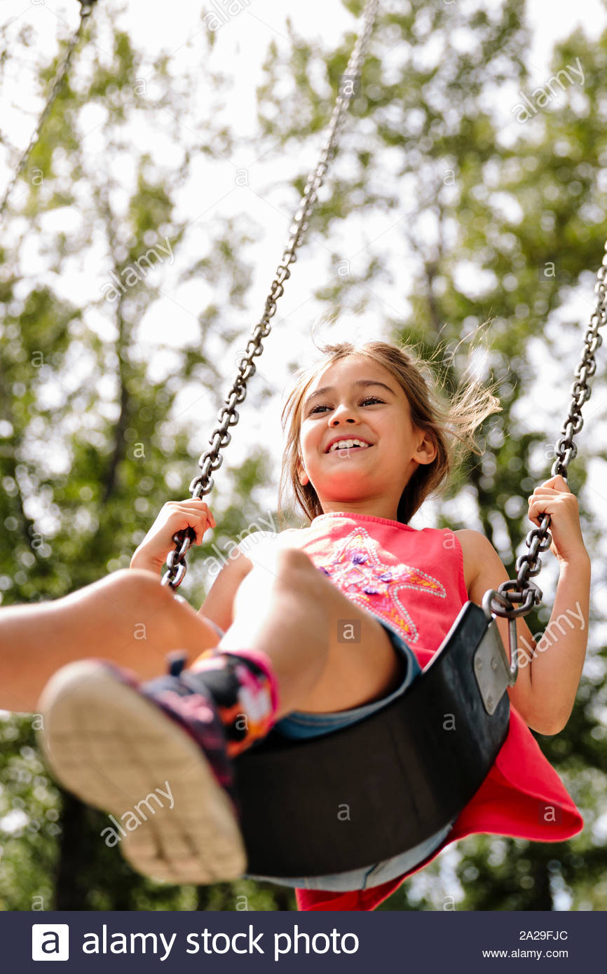 Candid portrait of young girl on swing in summer Stock Photo