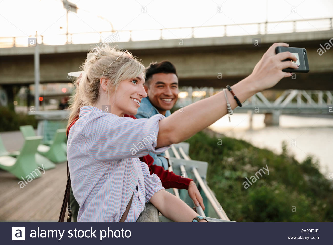 Happy young couple taking selfie with camera phone on urban boardwalk Stock Photo