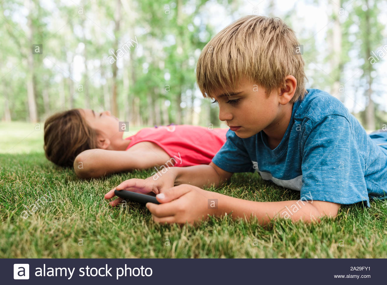 Boy lying on grass using smartphone Stock Photo