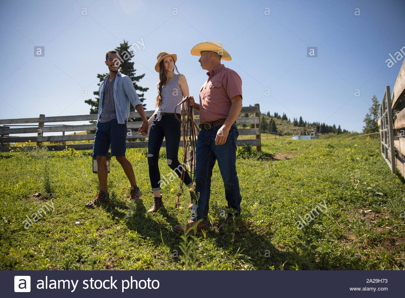 Father walking with young couple on ranch Stock Photo